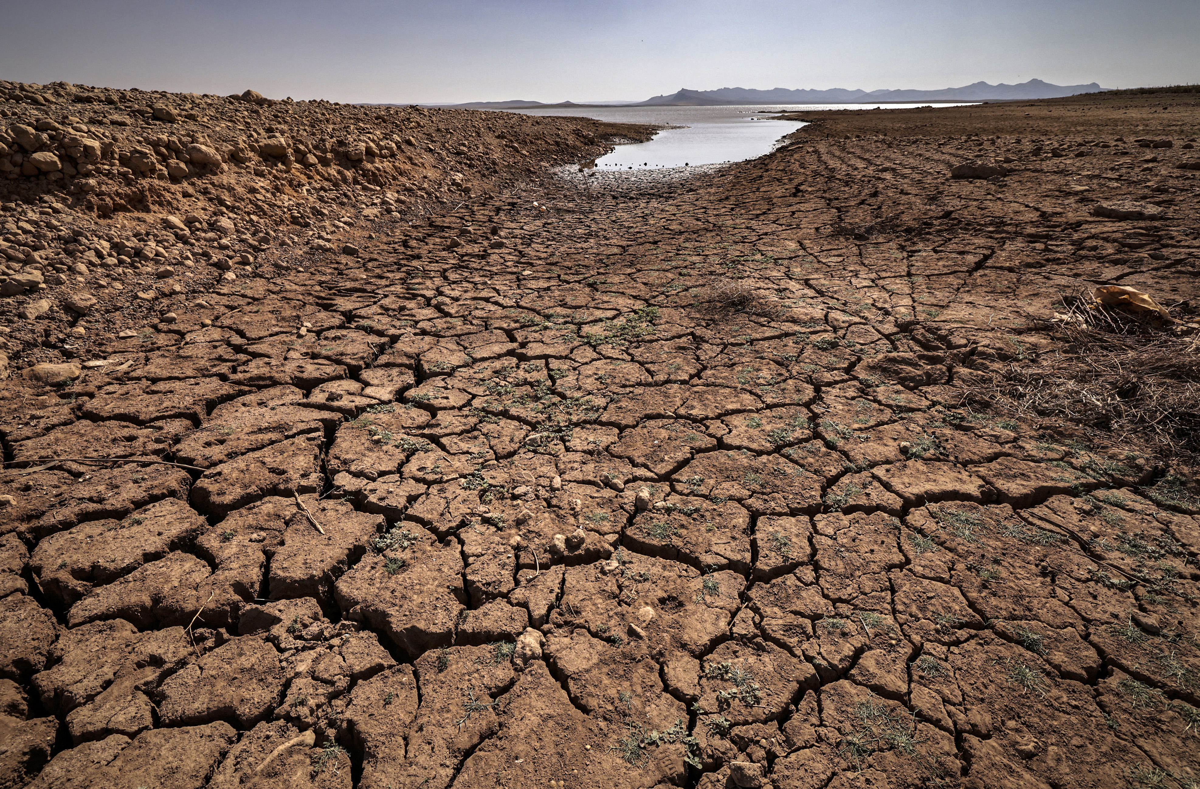 A picture shows cracked earth at al-Massira dam in Ouled Essi Masseoud village, some 140 kilometres (85 miles) south from Morocco's economic capital Casablanca, on August 8, 2022 amidst the country's worst drought in at least four decades. - Residents of Morocco's Ouled Essi Masseoud village are suffering from a series of successive droughts, prompting them to rely solely on sporadic supplies in public fountains and from private wells. The situation is critical, given the village's position in the agricultural province of Settat, near the Oum Errabia river and al-Massira dam, Morocco's second largest. Its reservoir supplies drinking water to several cities, including the three million people who live in Casablanca. But latest official figures show it is now filling at a rate of just five percent. (Photo by FADEL SENNA / AFP)