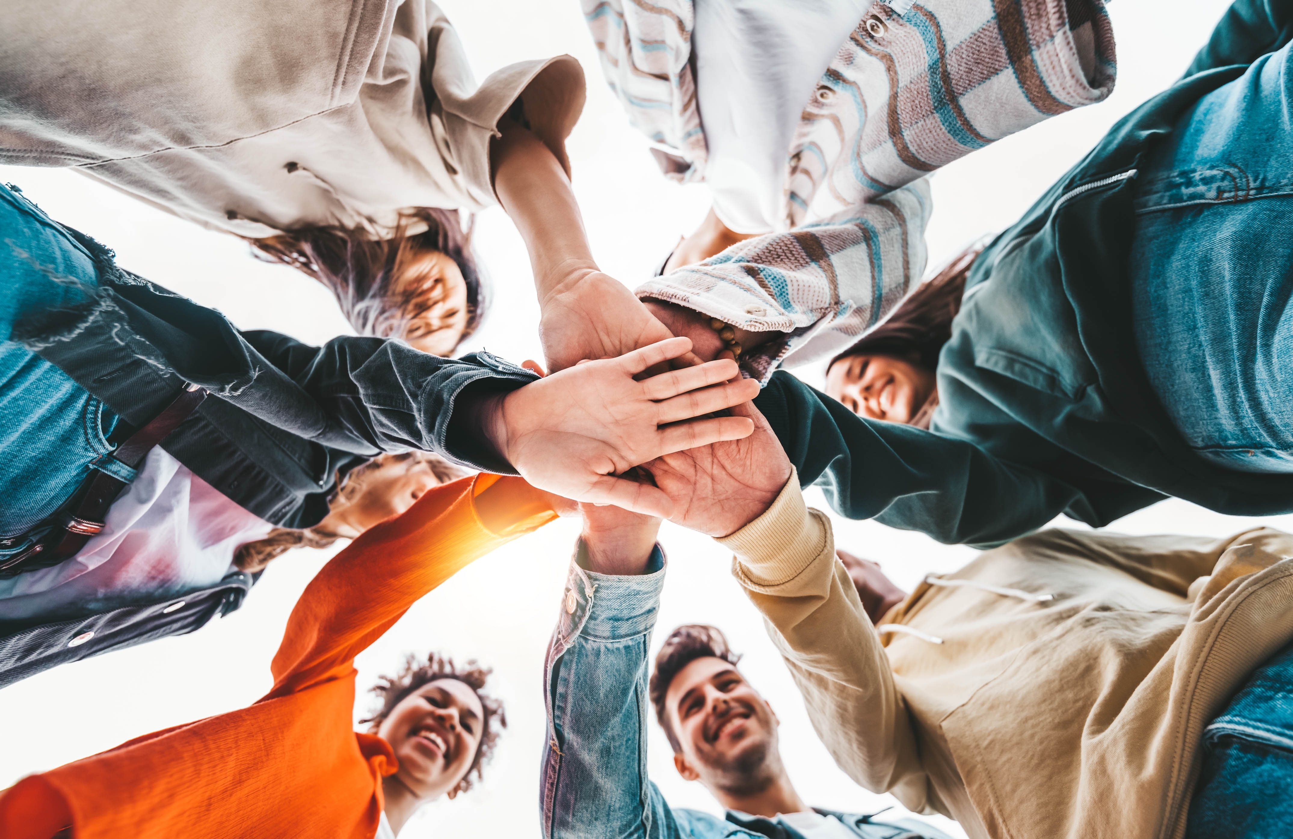 Un grupo de personas jóvenes en círculo tomados de la mano.