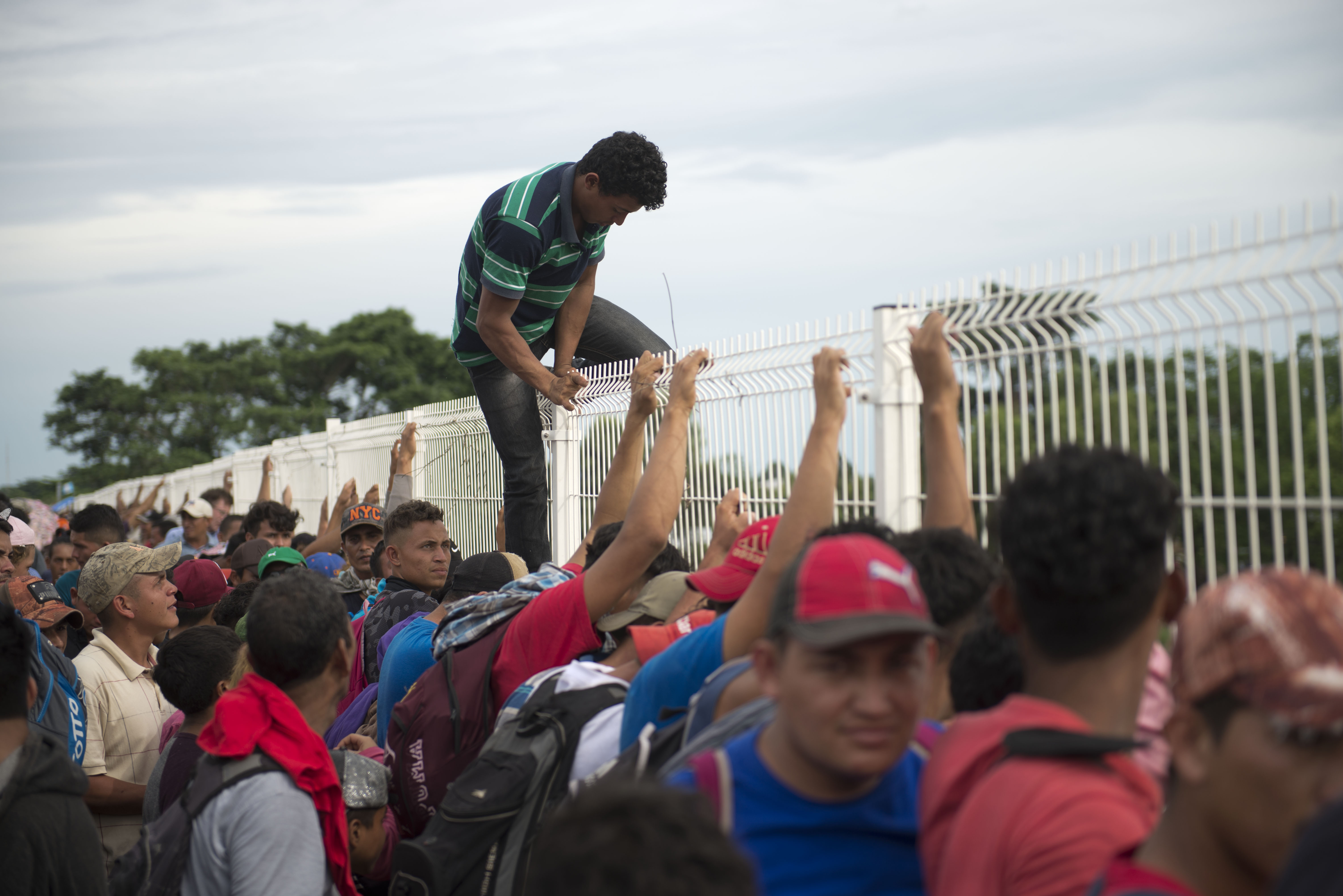 Un migrante cansado de esperar para cruzar a México, sube por una valla de un puente fronterizo para saltar al río Suchiate, en Tecún Umán, Guatemala. Foto: AP