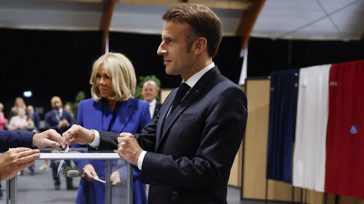 El presidente francés, Emmanuel Macron, introduce su voto en la urna junto a su esposa.