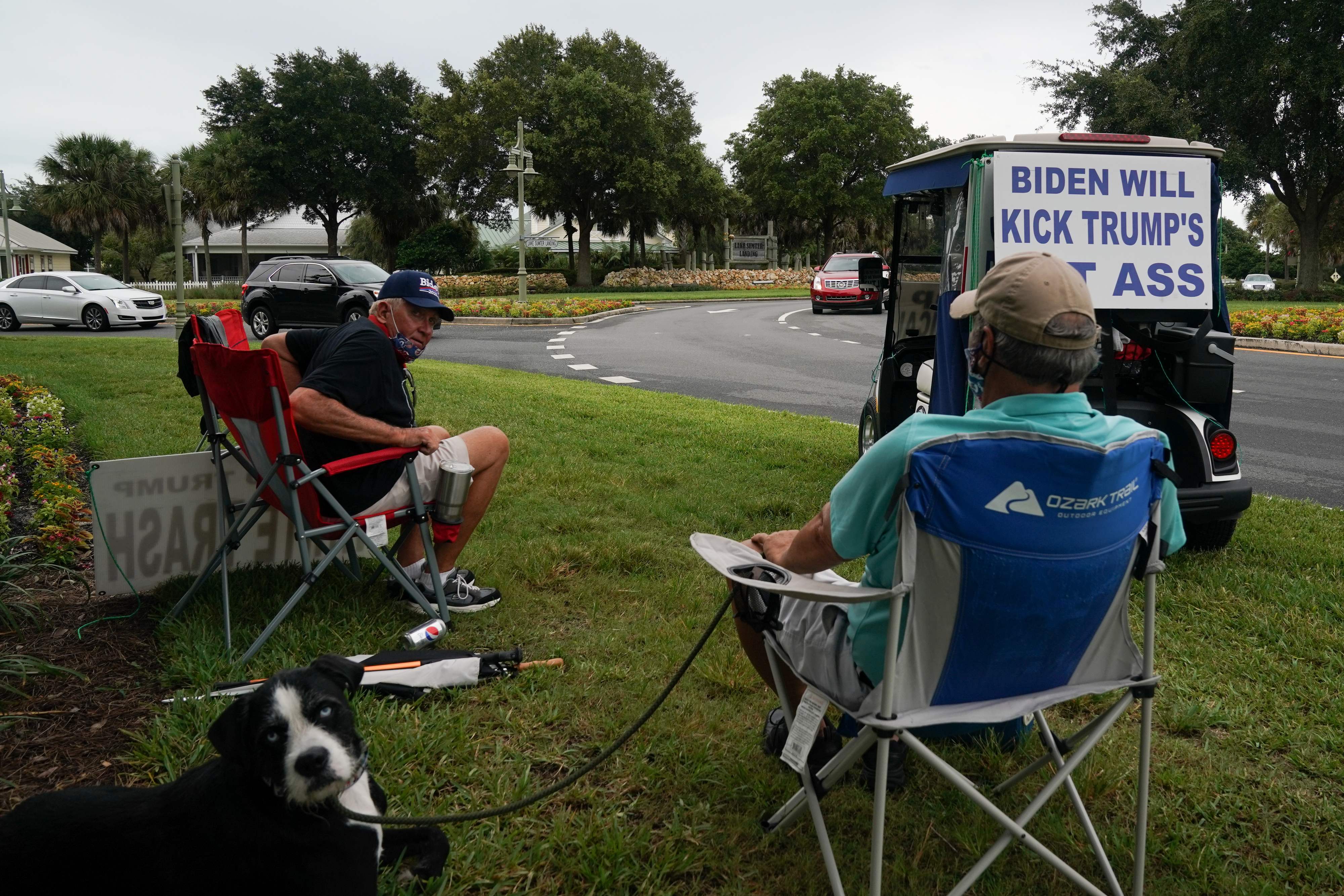 Casey Marr (R), a retiree from South New Jersey and Ed McGinty (L), a 71-year old retiree from Philadelphia, stage a daily protest against Donald Trump since his election in 2016, in Orlando, Florida on July 23, 2020. - Both protestors are living in "The Villages" the Trump stronghold retirement community in Florida, and McGinty endured multiple assaults and threats throughout his protest against Trump. With the help of his friend Casey Marr he has an extra set of eyes on hand to look after his safety. (Photo by Bryan R. Smith / AFP)