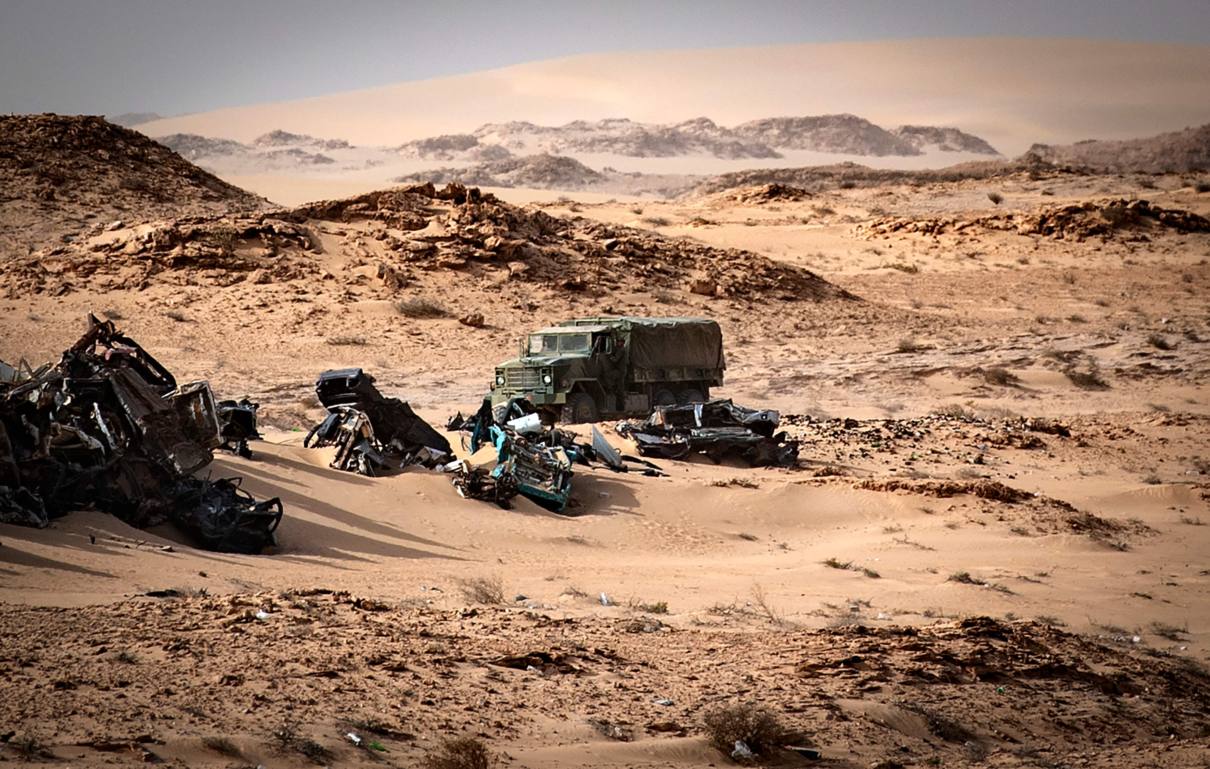 (FILES) In this file photo taken on November 24, 2020 a Moroccan army vehicle drives past car wreckages in Guerguerat located in the Western Sahara, after the intervention of the royal Moroccan armed forces in the area. - US President Donald Trump's surprise backing of Morocco's claim to sovereignty over disputed Western Sahara upended years of international consensus, but will this break a deadlock or inflame a conflict? (Photo by Fadel SENNA / AFP)