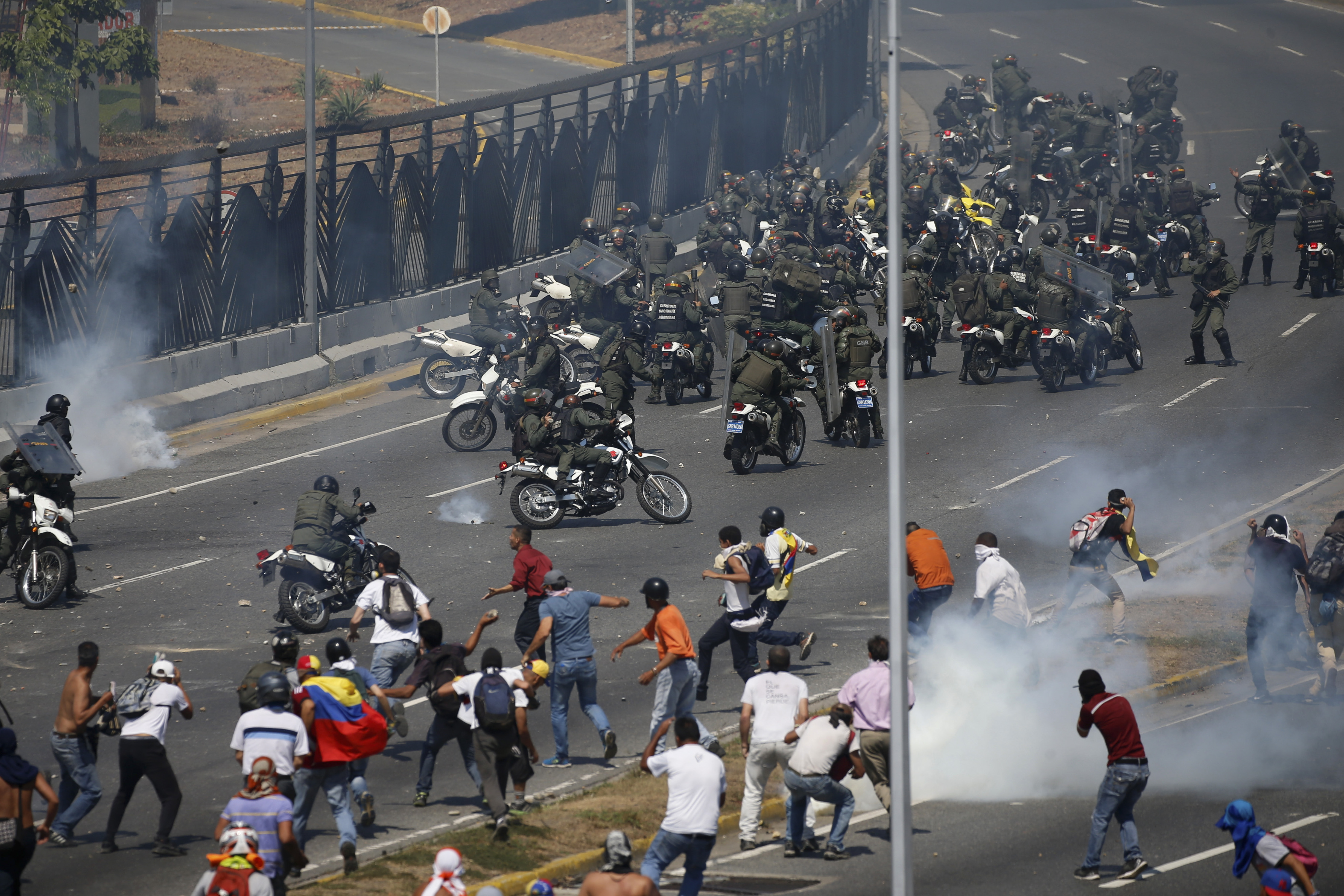 Opponents to Venezuela's President Nicolas Maduro confront loyalist Bolivarian National Guard troops firing tear gas at them outside La Carlota military airbase in Caracas, Venezuela, Tuesday, April 30, 2019. Venezuelan opposition leader Juan Guaidó took to the streets with activist Leopoldo Lopez and a small contingent of heavily armed troops early Tuesday in a bold and risky call for the military to rise up and oust socialist leader Nicolas Maduro. (AP Photo/Fernando Llano)