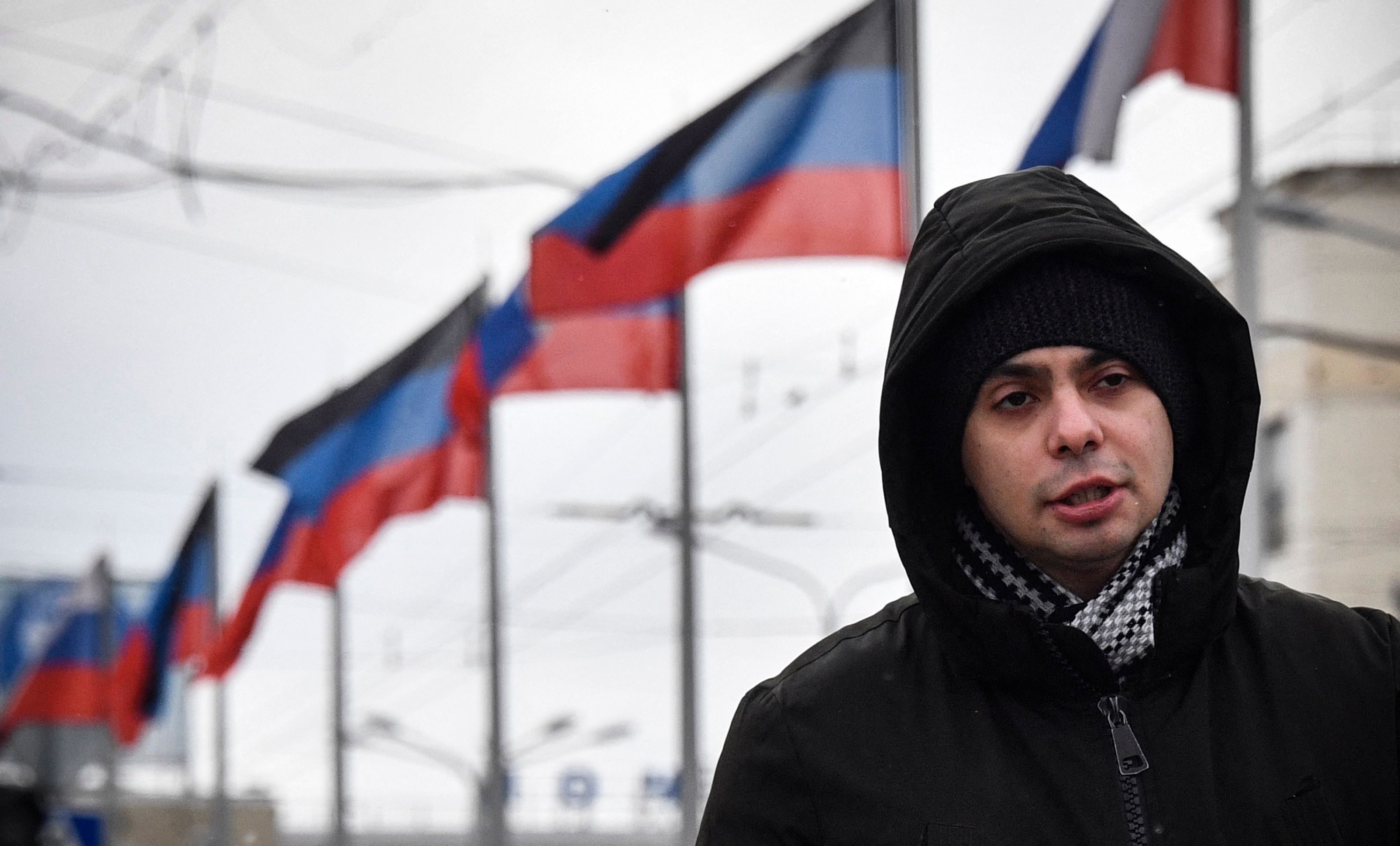 A man walks past Russian and Donetsk People's Republic flags in Donetsk, the capital of the self-proclaimed state of the Donetsk People's Republic (PDR) in eastern Ukraine, on January 18, 2022. (Photo by Alexander NEMENOV / AFP)