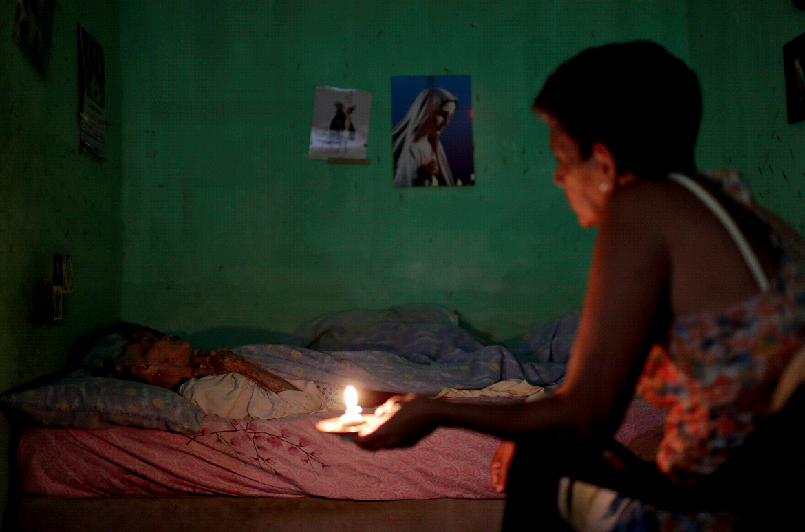 Ninoska Blanco vela a su madre enferma en Caracas, Venezuela, con una vela por la falta de electricidad.