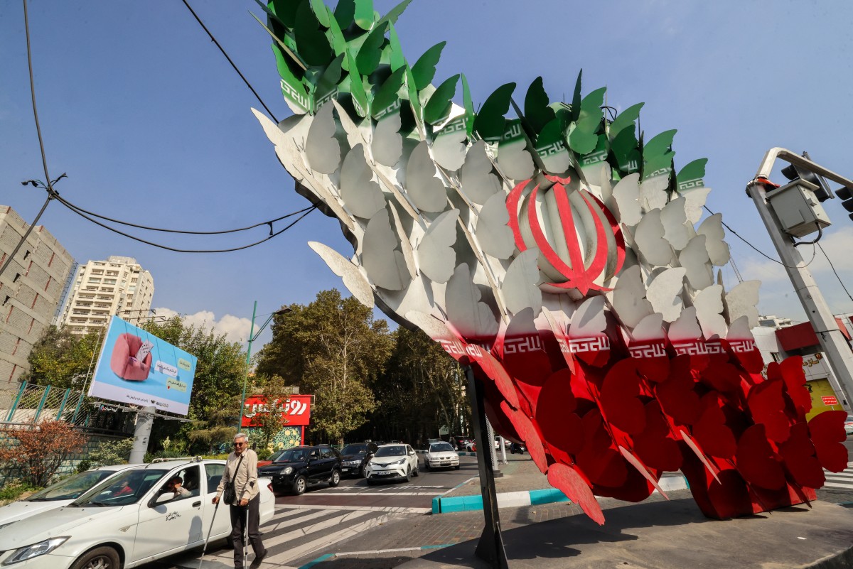 El tráfico pasa frente a una instalación que representa mariposas formando la bandera nacional de Irán en Teherán, el 21 de octubre de 2026.