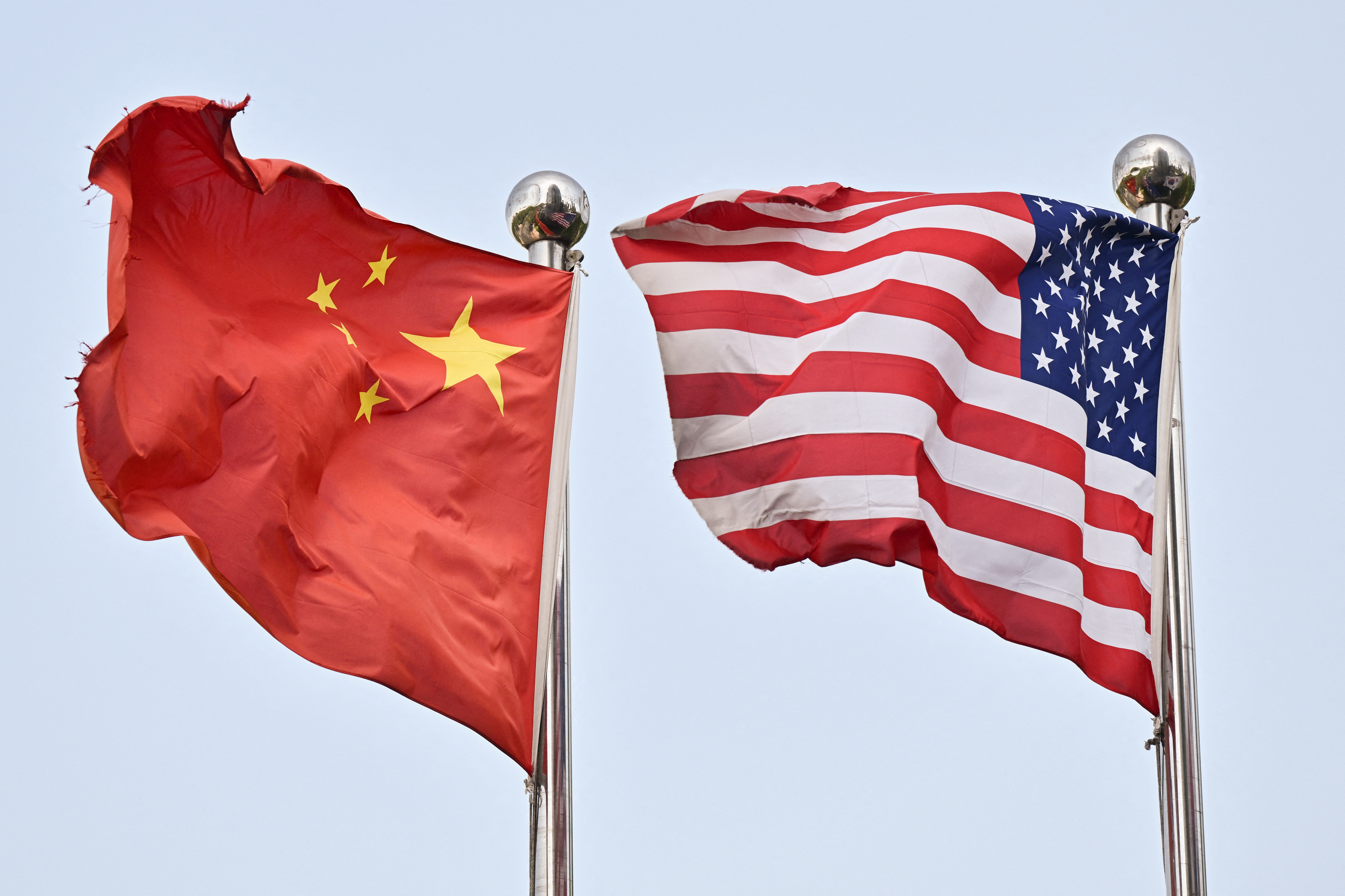 Banderas de China y Estados Unidos ondeando juntas sobre mástiles metálicos, en el contexto de nuevas negociaciones comerciales bilaterales en Londres.