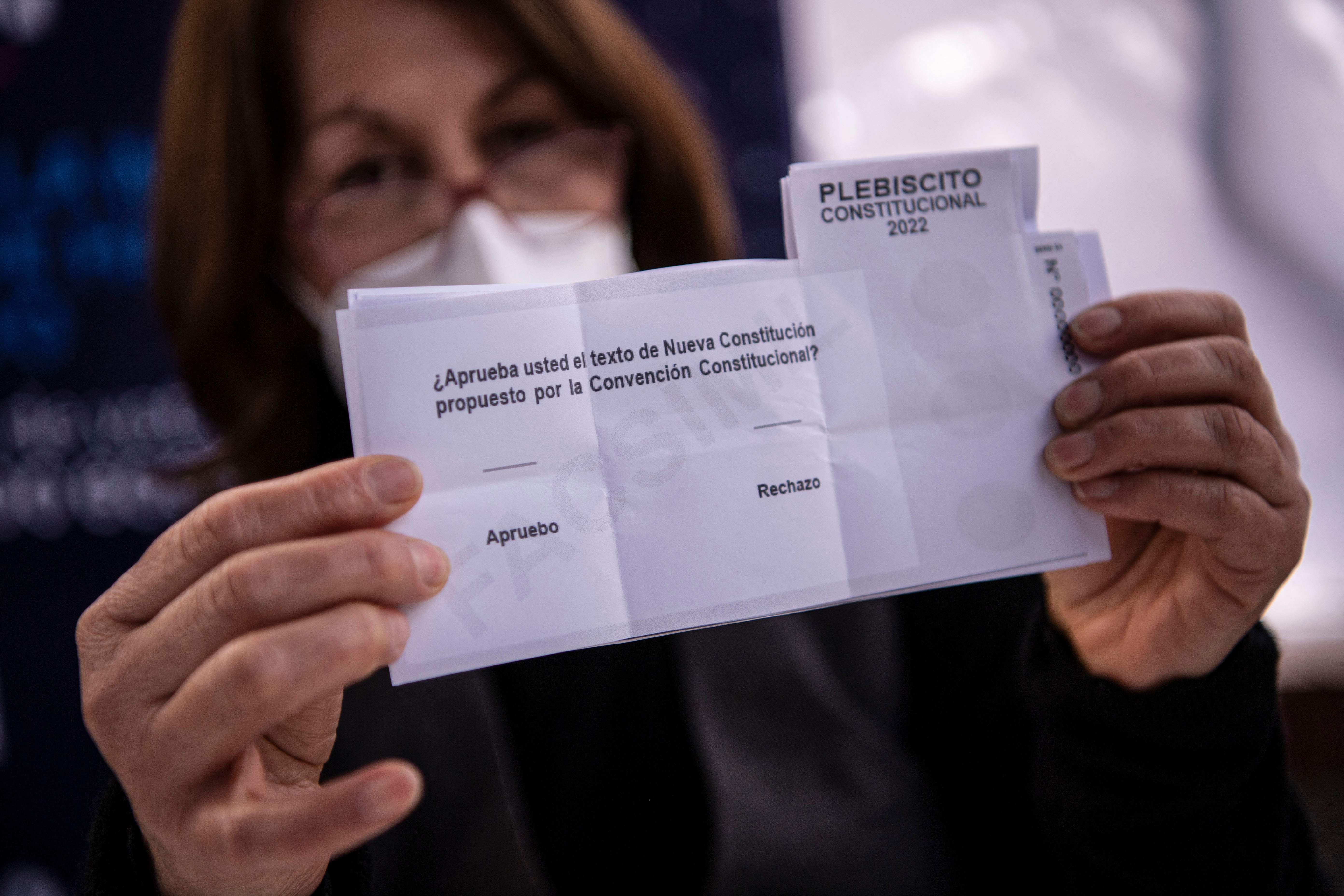 A worker of the municipality of Providencia shows a ballot at a polling station ahead of next Sunday's referendum in Santiago on September 2, 2022. - Chileans will vote Sunday on whether to adopt a new constitution and shift from a market-driven society to a more welfare-based one. The proposed draft aims to replace the current constitution, written during the Augusto Pinochet dictatorship (1973-1990), that -- despite several successive reforms -- is still considered an obstacle to any fundamental social changes. (Photo by MARTIN BERNETTI / AFP)
