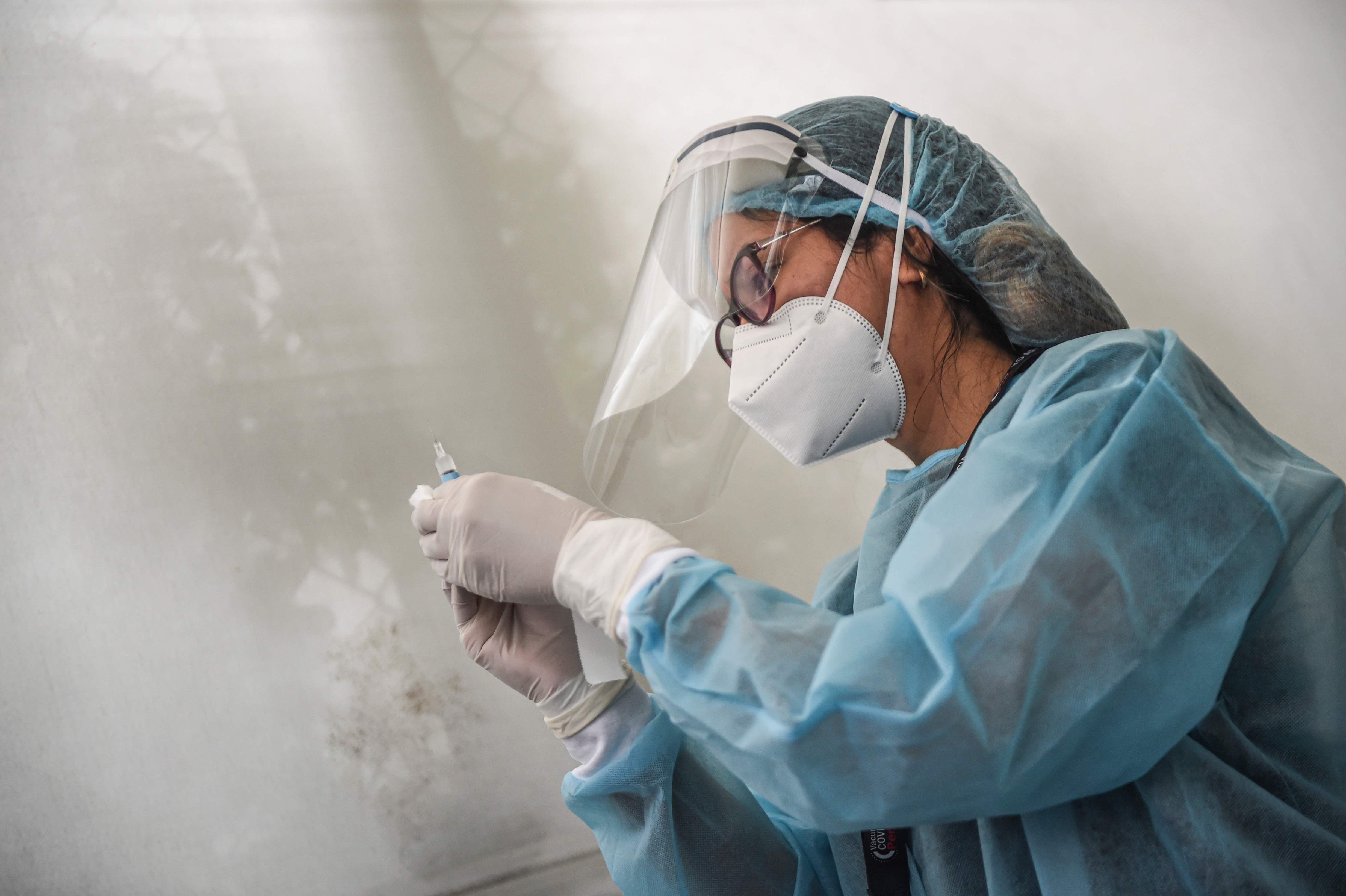 TOPSHOT - A health worker prepares a syringe to inoculate a volunteer with a COVID-19 vaccine produced by the Chinese Sinopharm during its trial at the Clinical Studies Center of the Cayetano Heredia University in Lima on December 09, 2020. (Photo by ERNESTO BENAVIDES / AFP)