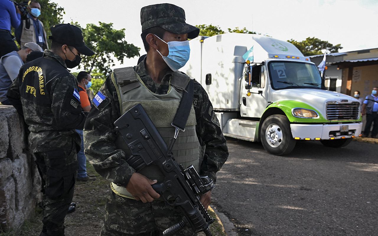 Soldiers stand guard as trucks distributing electoral material leave the National Institute of Professional Formation (INFOP), in Tegucigalpa, on November 23, 2021. - Honduras holds general elections on November 28. (Photo by Orlando SIERRA / AFP)