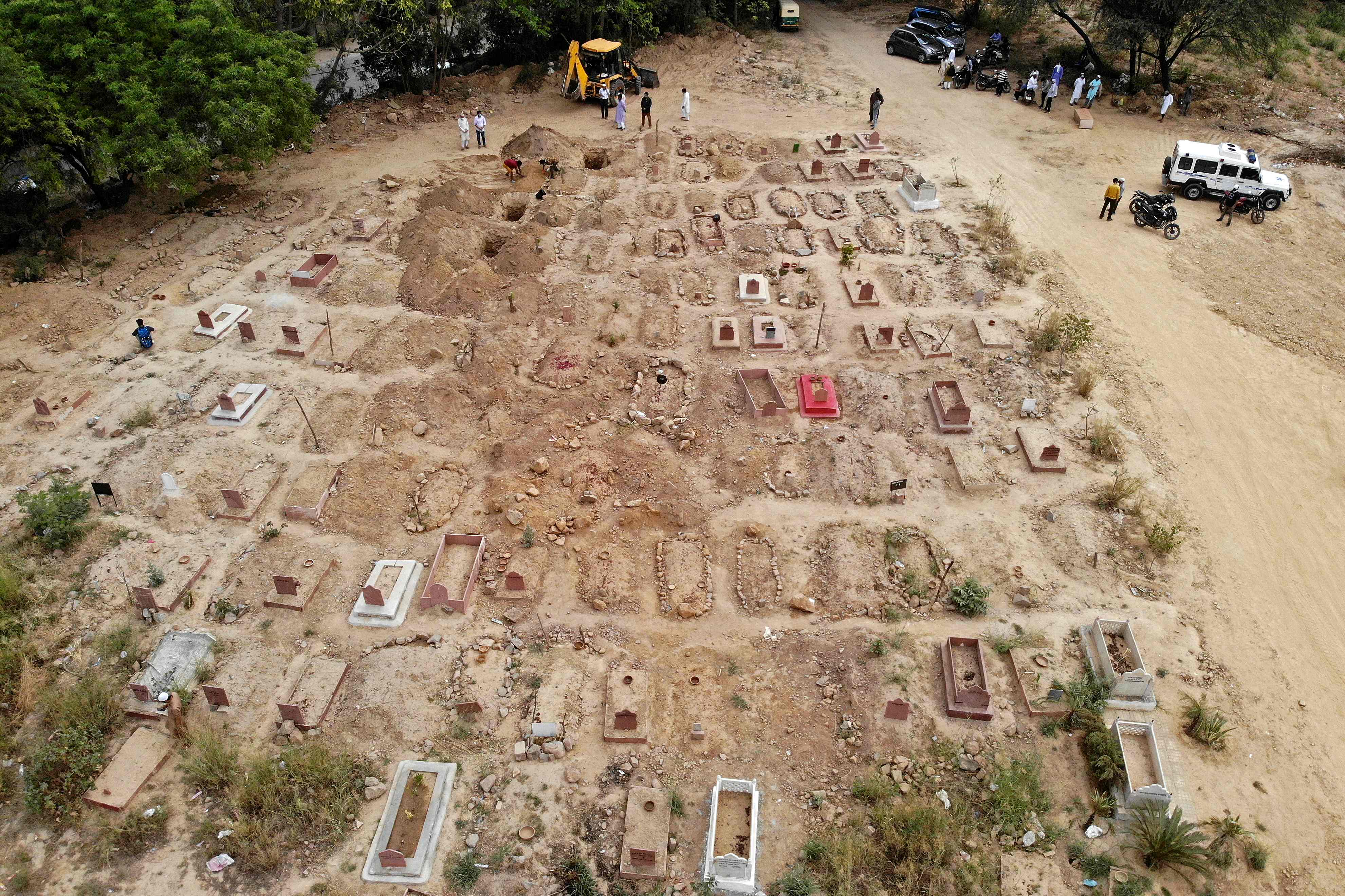 In this aerial picture taken on April 16, 2021, relatives and friends gather to bury the dead bodies of Covid-19 coronavirus victims at a graveyard in New Delhi. (Photo by Archana THIYAGARAJAN / AFP)