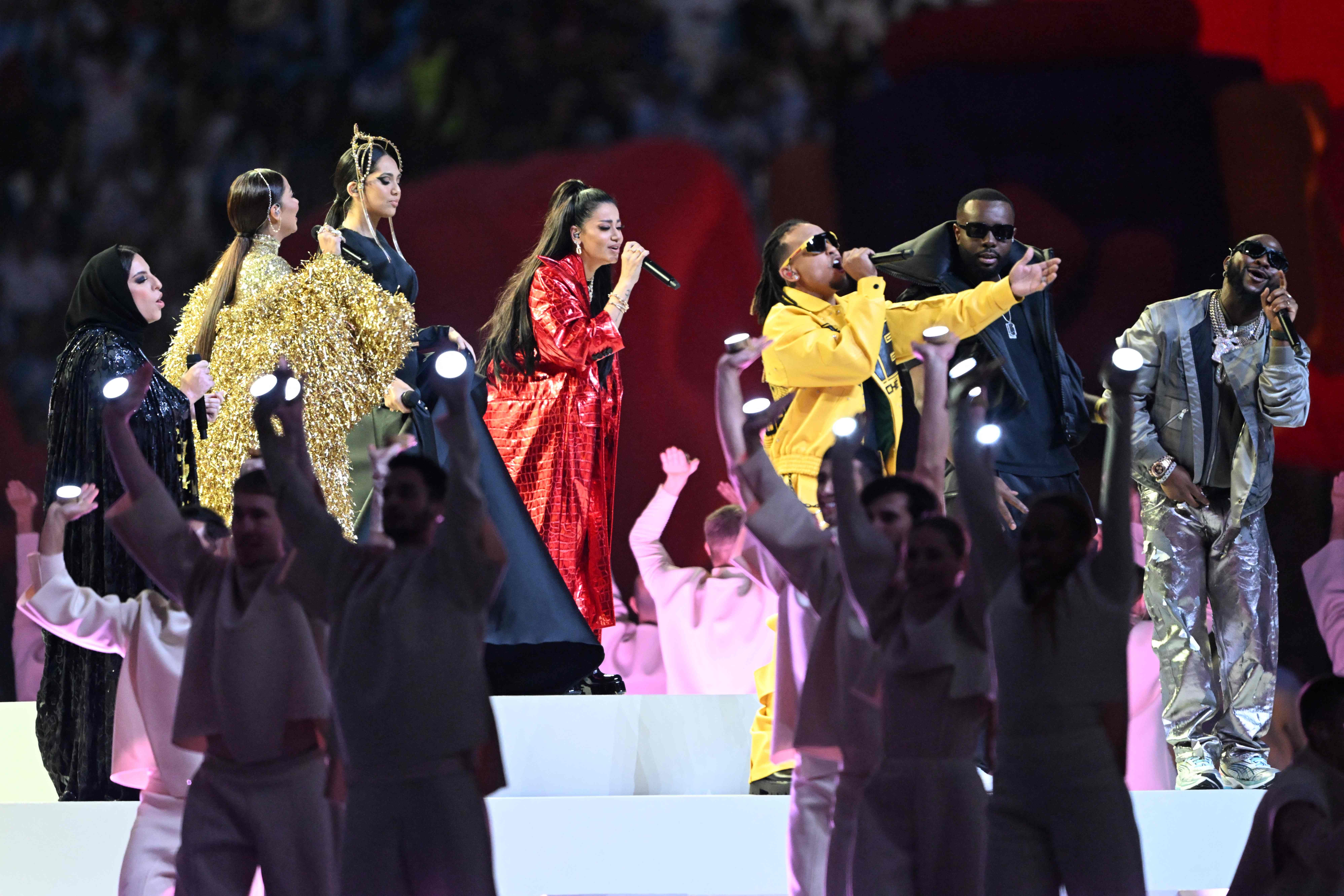 Puerto Rican singer Ozuna (C) performs with Iraqi singer Rahma Riad (4thL), Congolese-French rapper Gims (2ndR) and US-Nigerian singer Davido (R) during the closing ceremony ahead of the Qatar 2022 World Cup final football match between Argentina and France at Lusail Stadium in Lusail, north of Doha on December 18, 2022. (Photo by Kirill KUDRYAVTSEV / AFP)