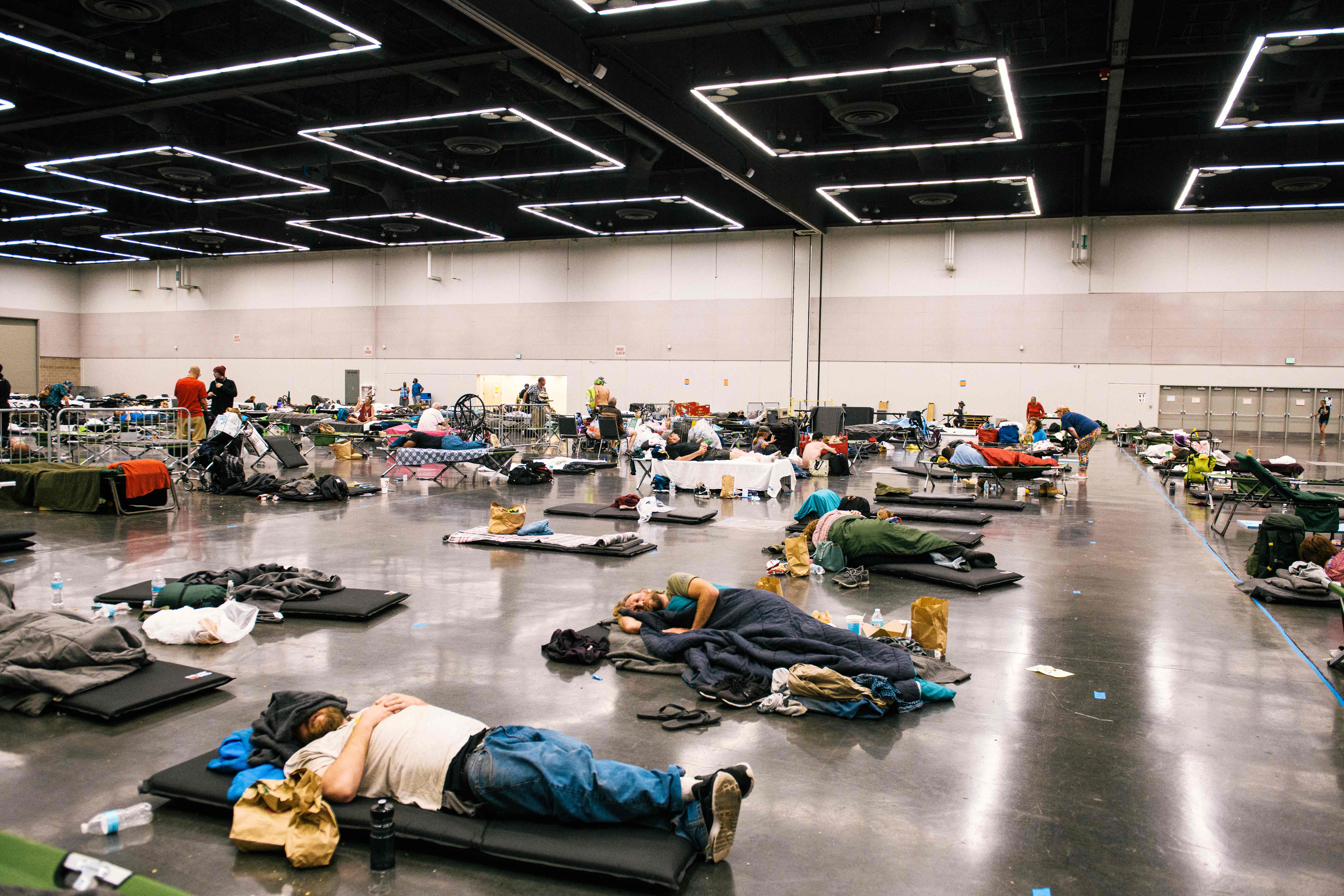 People rest at the Oregon Convention Center cooling station in Oregon, Portland on June 28, 2021, as a heatwave moves over much of the United States. - Swathes of the United States and Canada endured record-setting heat on June 27, 2021, forcing schools and Covid-19 testing centers to close and the postponement of an Olympic athletics qualifying event, with forecasters warning of worse to come. The village of Lytton in British Columbia broke the record for Canada's all-time high, with a temperature of 46.6 degrees Celsius (116 Fahrenheit), said Environment Canada. (Photo by Kathryn Elsesser / AFP)