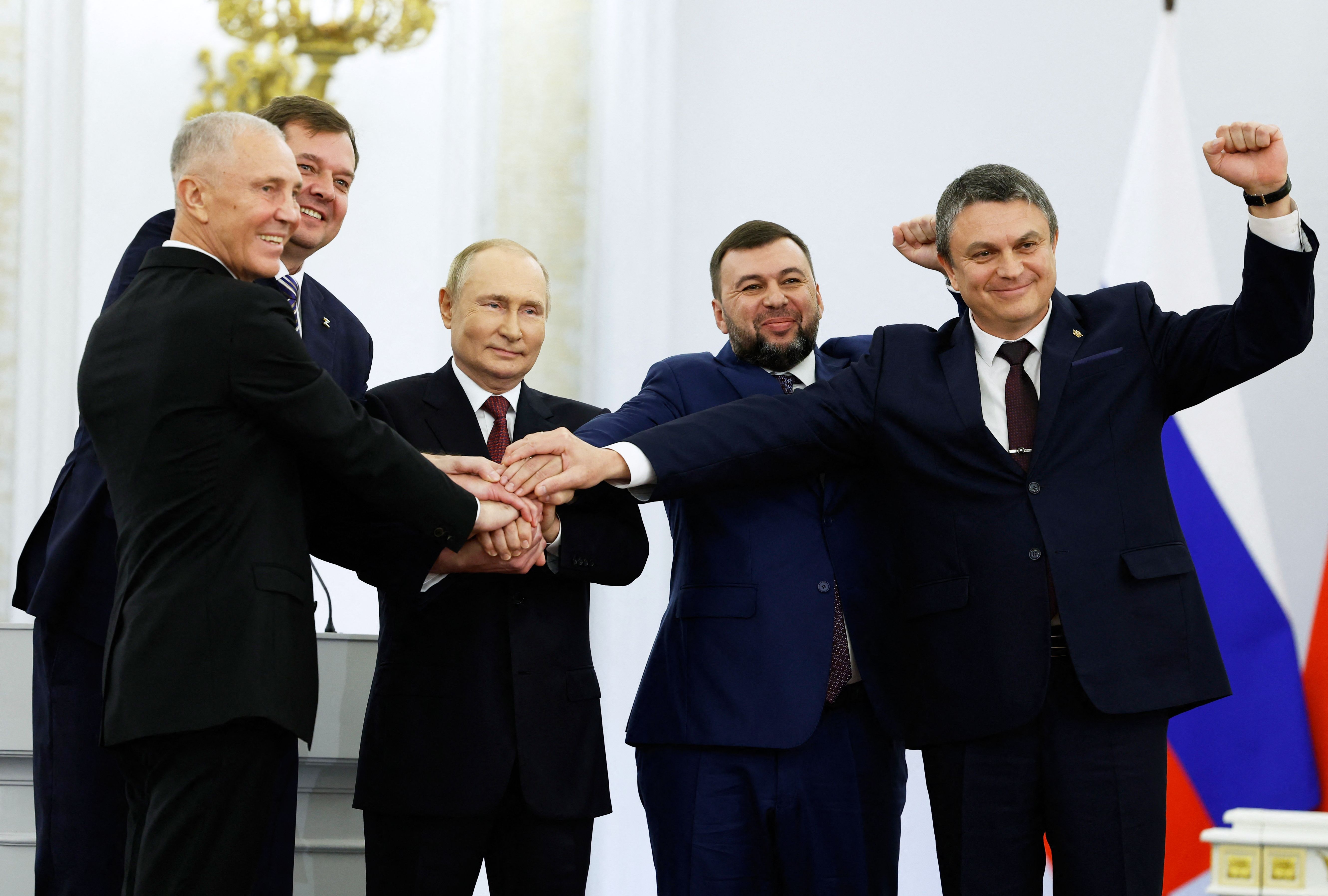 (L-R) The Moscow-appointed heads of Kherson region Vladimir Saldo and Zaporizhzhia region Yevgeny Balitsky, Russian President Vladimir Putin, Donetsk separatist leader Denis Pushilin and Lugansk separatist leader Leonid Pasechnik join hands after signing treaties formally annexing four regions of Ukraine Russian troops occupy, at the Kremlin in Moscow on September 30, 2022. (Photo by Dmitry ASTAKHOV / SPUTNIK / AFP)