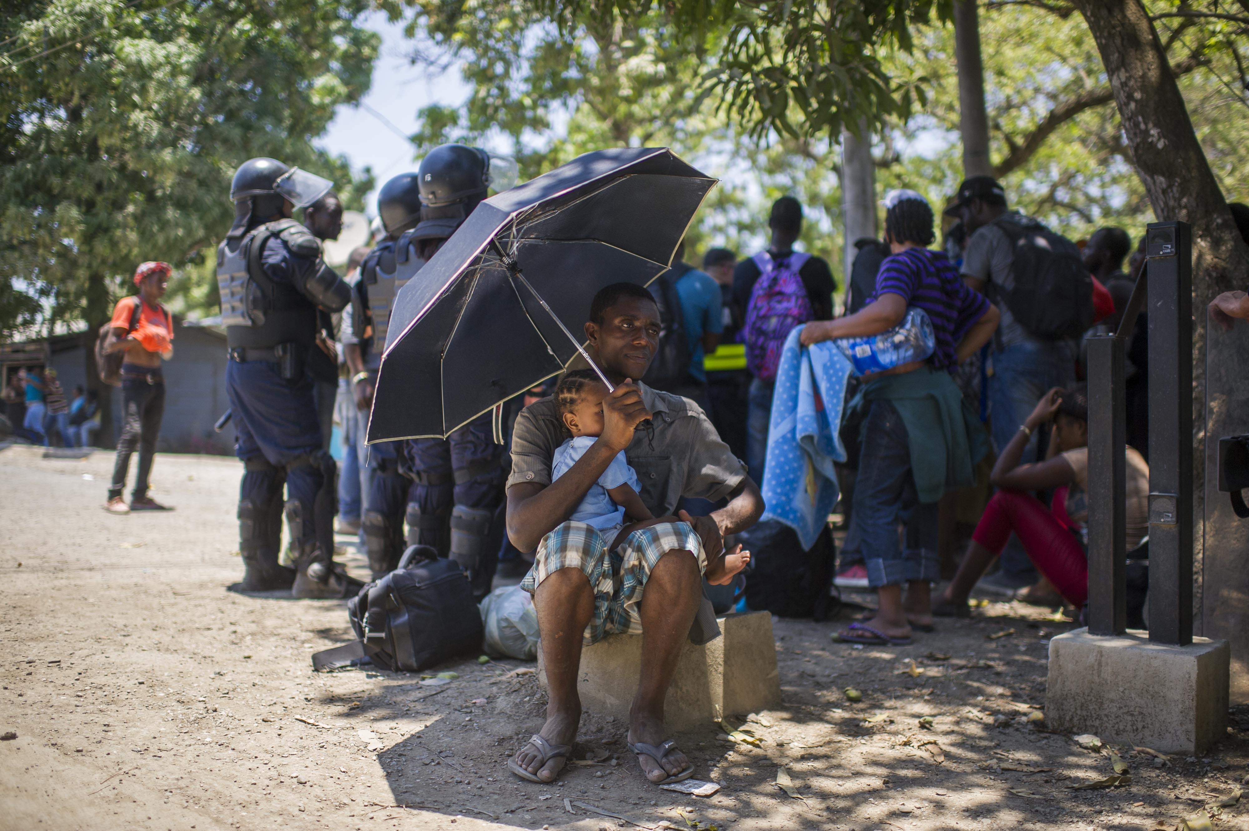 Un africano con su hija espera por pasar la frontera con Nicaragua ante la mirada de la Policía costarricense, en Peñas Blancas.