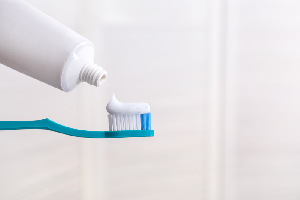 Un cepillo dental, se le está colocando pasta.