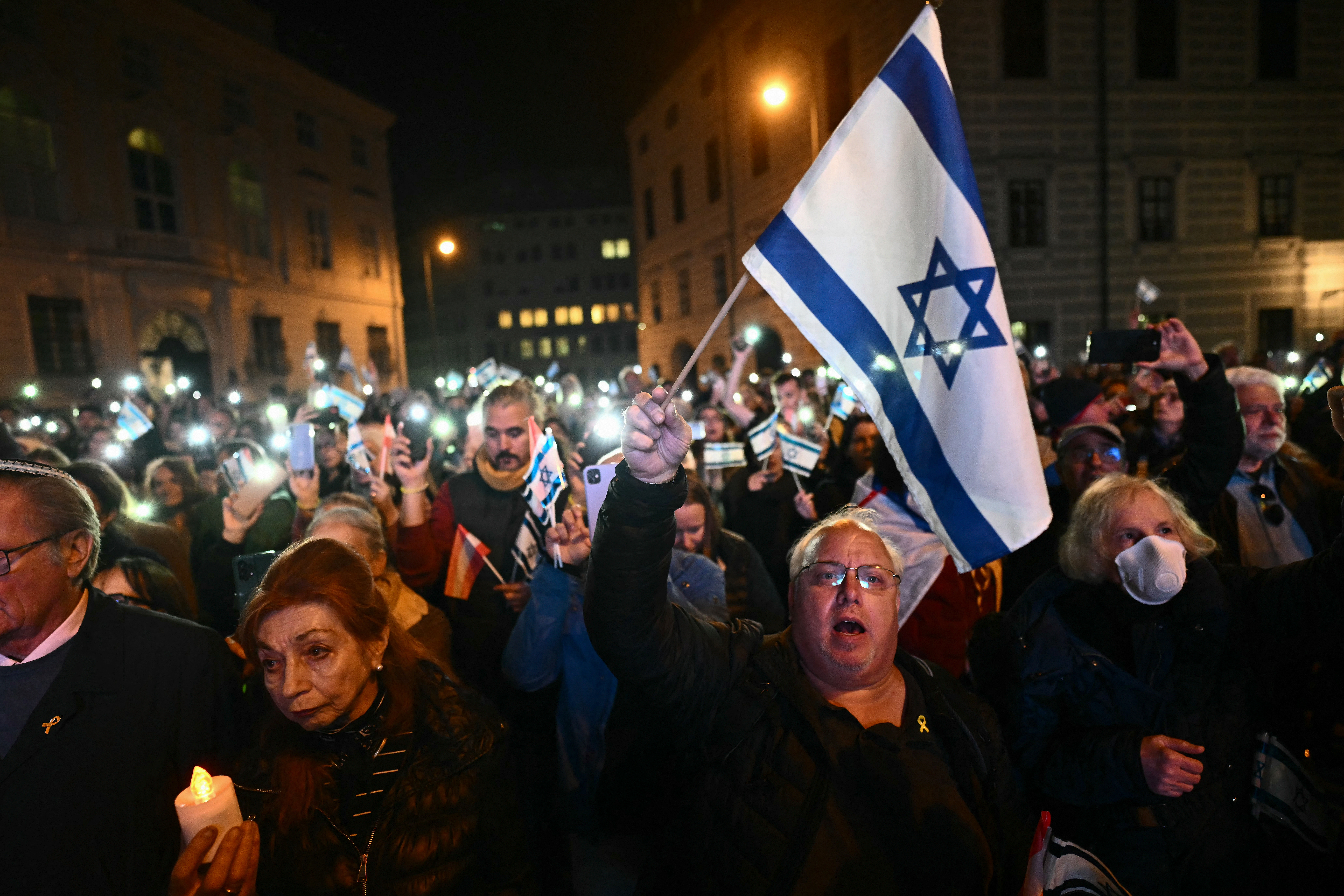 La gente enciende sus teléfonos móviles durante una ceremonia de conmemoración de las víctimas del ataque de Hamas del 7 de octubre en la plaza Ballhaus en Viena, Austria
