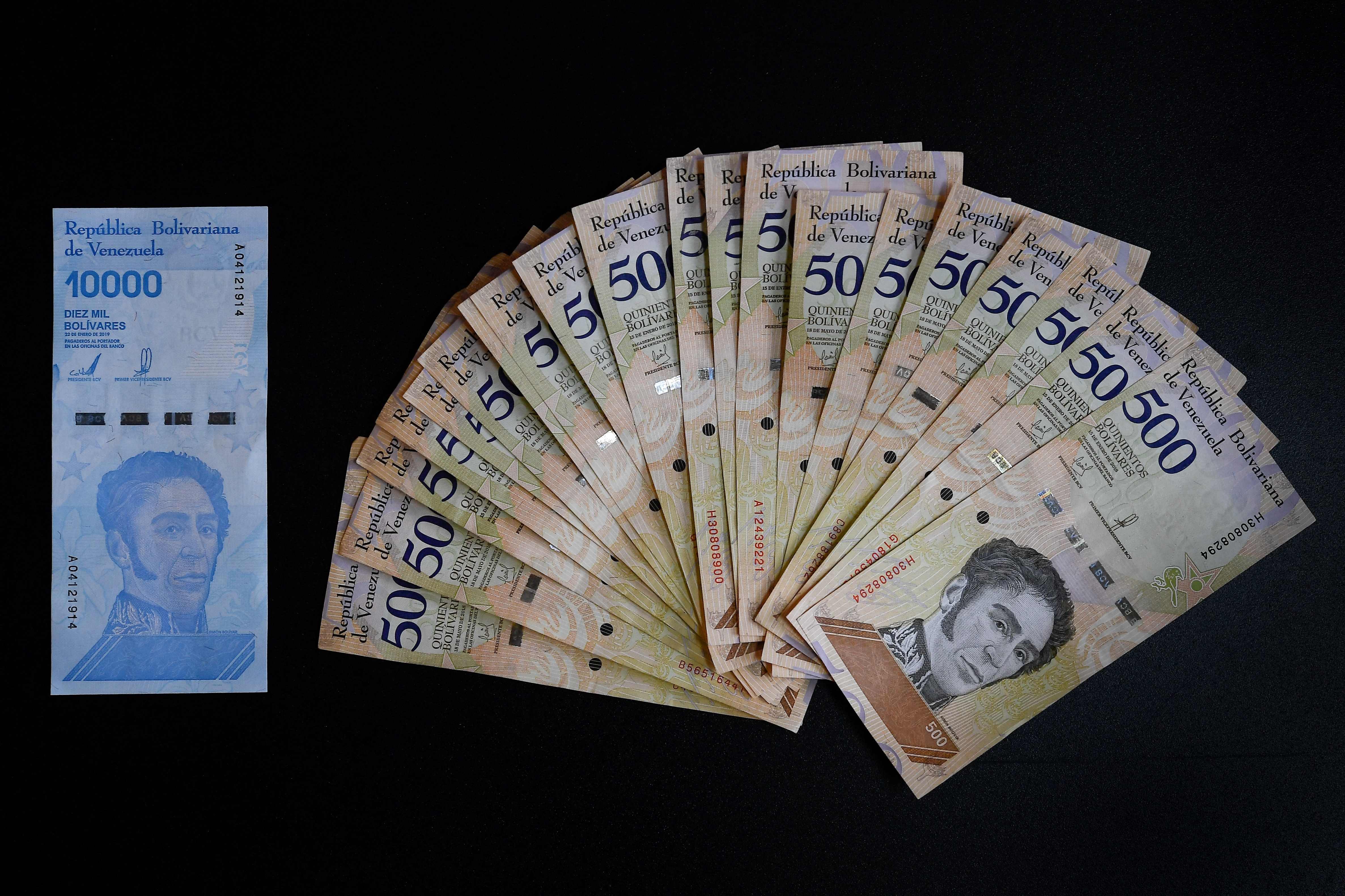 (FILES) File photo taken on June 14, 2019 of a new ten thousand Bolivar-note (L) and its equivalent in current five hundred Bolivar-bills in Caracas. - Venezuela will eliminate six ceros from its currency and announced new bills, the Central Bank informed on August 5, 2021. (Photo by Federico PARRA / AFP)