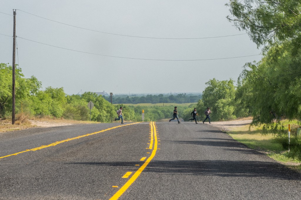 LA JOYA, TEXAS - MAY 03: A group of migrants run across a street after illegally crossing into the U.S. from Mexico on May 03, 2022 in La Joya, Texas. Texas Gov. Greg Abbott's "Lone Star Operation" directed approximately 10,000 members of the national guard to assist law enforcement with patrol and border apprehensions. Towns along the southern border continue making preparations as Title 42 is scheduled to end on May 23rd. Brandon Bell/Getty Images/AFP (Photo by Brandon Bell / GETTY IMAGES NORTH AMERICA / Getty Images via AFP)