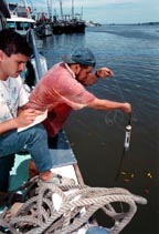 Los pescadores Hernán Zúñiga (camiseta roja) y Wéiner Alpízar utilizan -en un barco Long Line- un termómetro especial para medir la temperatura del agua y saber la ubicación de los peces.