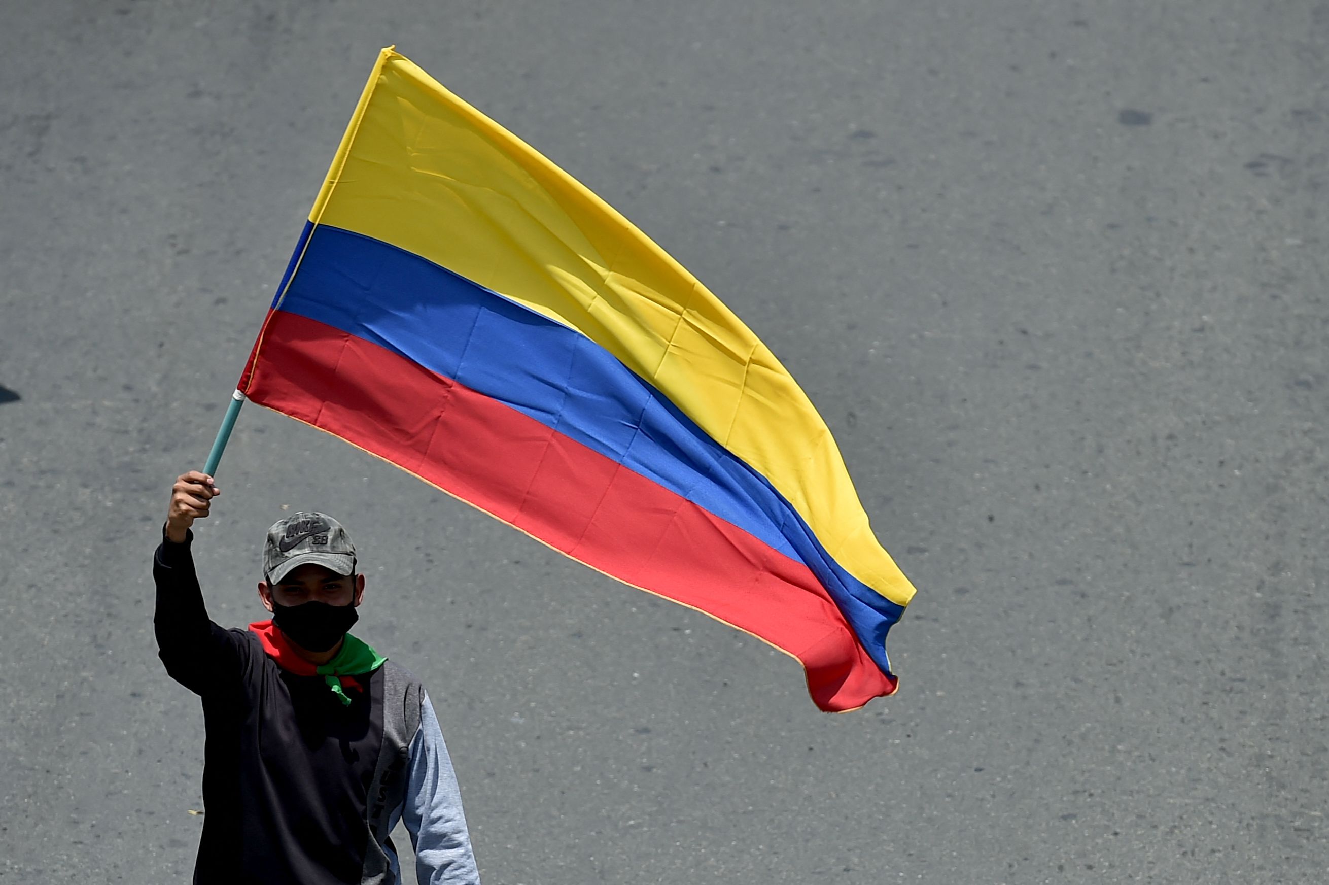 An indigenous man waves a Colombian flag during a protest against President Ivan Duque's government in Cali, Colombia on May 5, 2021. - Thousands of people returned to the streets of Colombia on Wednesday in rejection of the government of Ivan Duque, who has completed a week of pressure with demonstrations that turned violent in some cities and left some twenty people dead. (Photo by Luis ROBAYO / AFP)