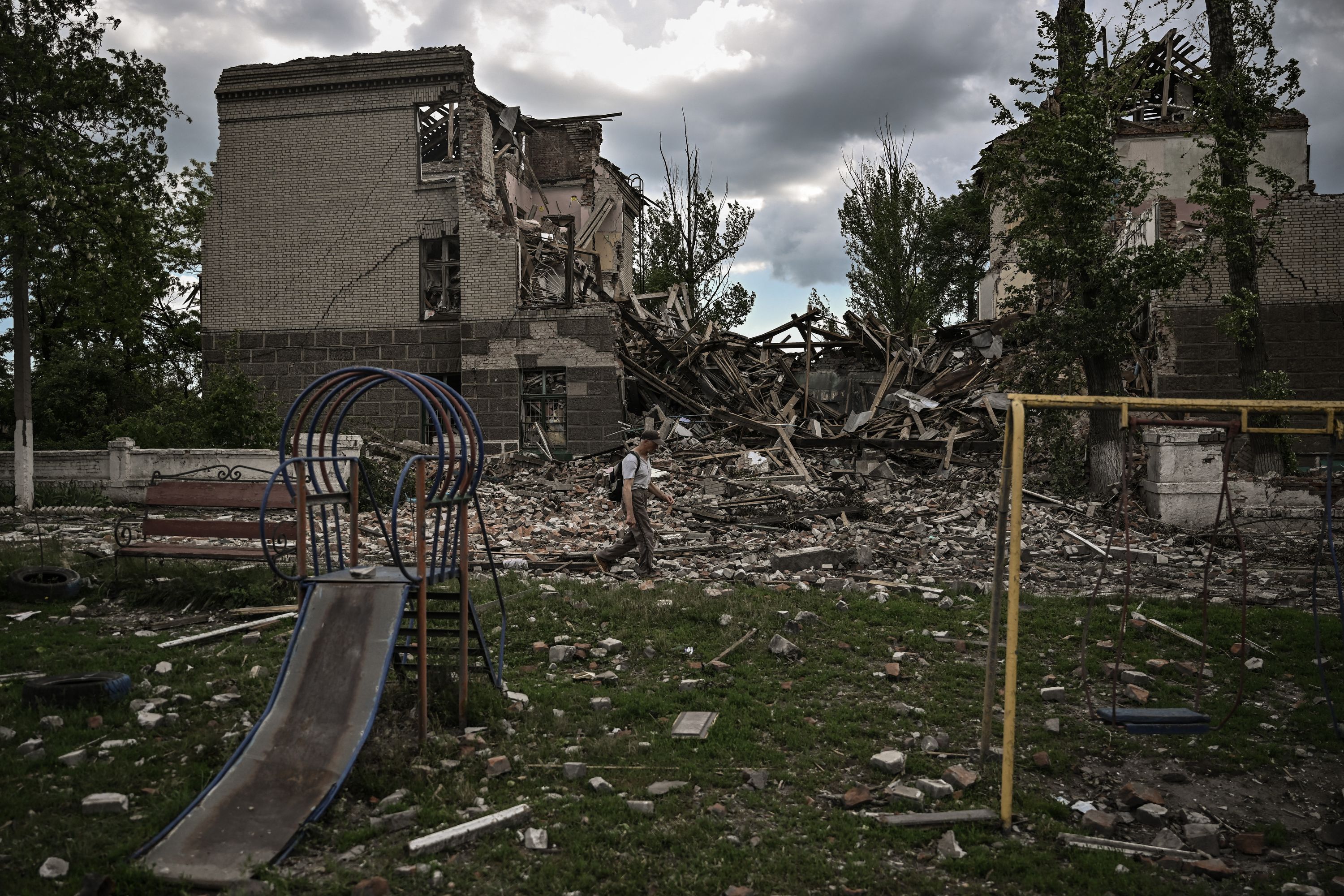 TOPSHOT - A man walks in front of a destroyed school in the city of Bakhmut, in the eastern Ukranian region of Donbas on May 28, 2022, on the 94th day of Russia's invasion of Ukraine. (Photo by ARIS MESSINIS / AFP)