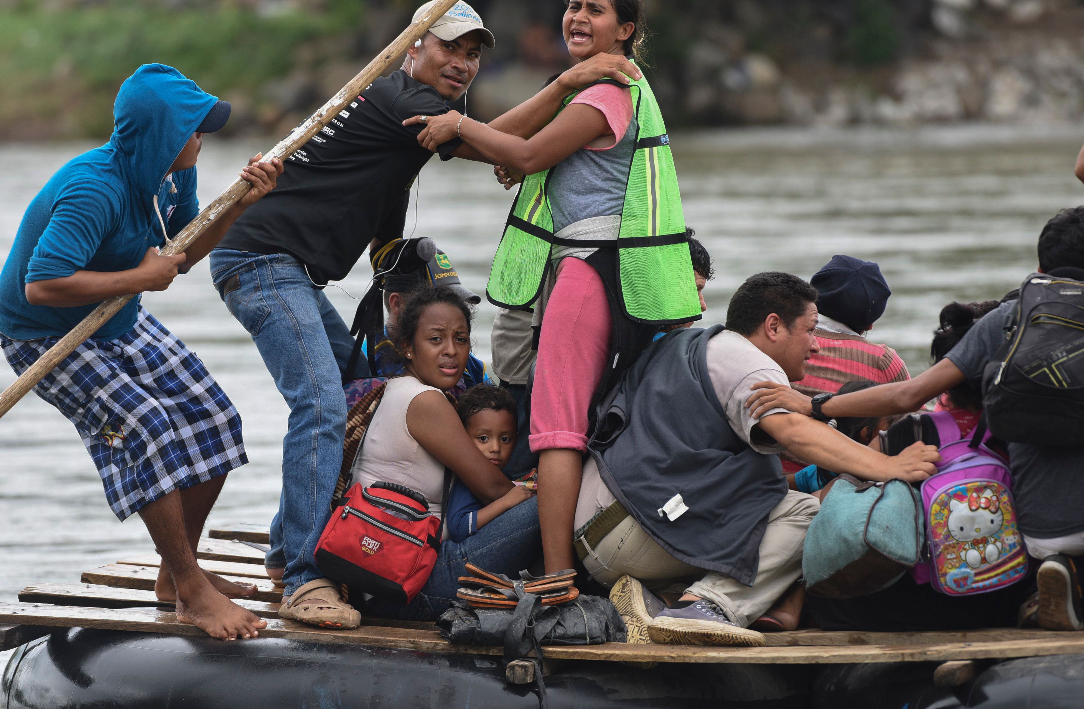 Honduran migrants taking part in a caravan heading to the US, cross the Suchiate River, natural border between Guatemala and Mexico, in a makeshift raft, in Ciudad Tecun Uman, Guatemala, on October 20, 2018. - Thousands of migrants who forced their way through Guatemala's northwestern border and flooded onto a bridge leading to Mexico, where riot police battled them back, on Saturday waited at the border in the hope of continuing their journey to the United States. (Photo by ORLANDO SIERRA. / AFP)