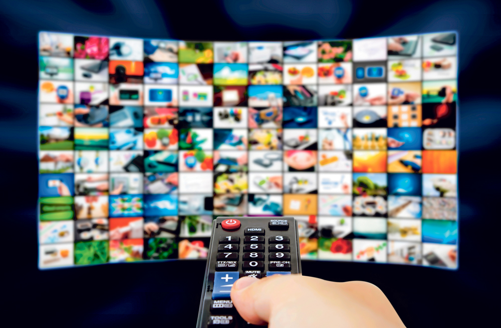 Big LCD panel with television stream images and remonte control in hand