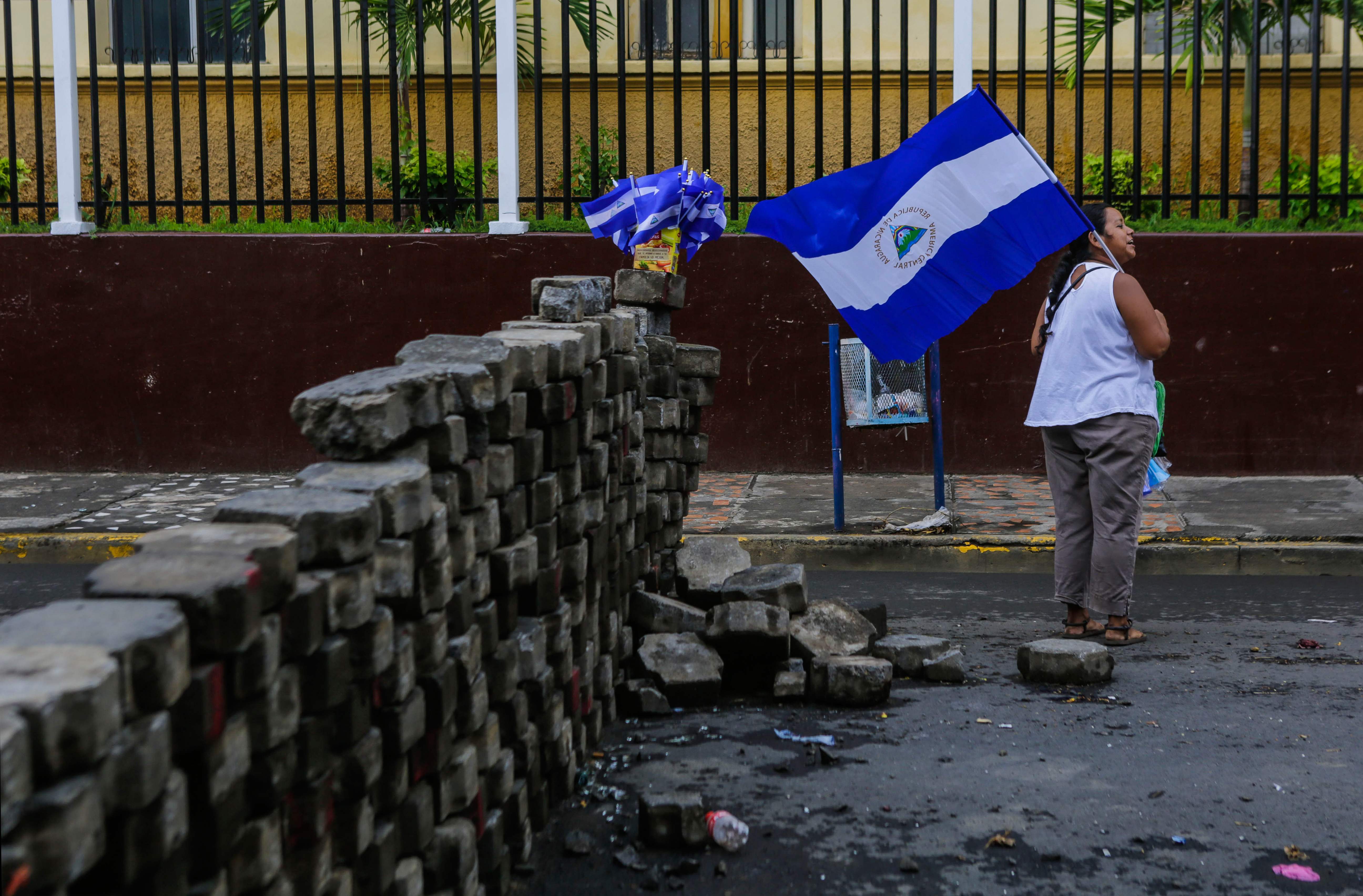 TOPSHOT - A woman holds a Nicaraguan national flag next to a barricade in the neighbourhood of Monimbo, in Masaya, a city some 35 km from Managua, on May 21, 2018.
Masaya, once a cradle of the Sandinista movement, is now a hotbed of resistance to President Daniel Ortega. Initially triggered by now-aborted reforms to the near-bankrupt social security system, unrest in Nicaragua has broadened into a rejection by many of Ortega and his wife and vice president Rosario Murillo, seen as autocratic. / AFP PHOTO / Inti OCON