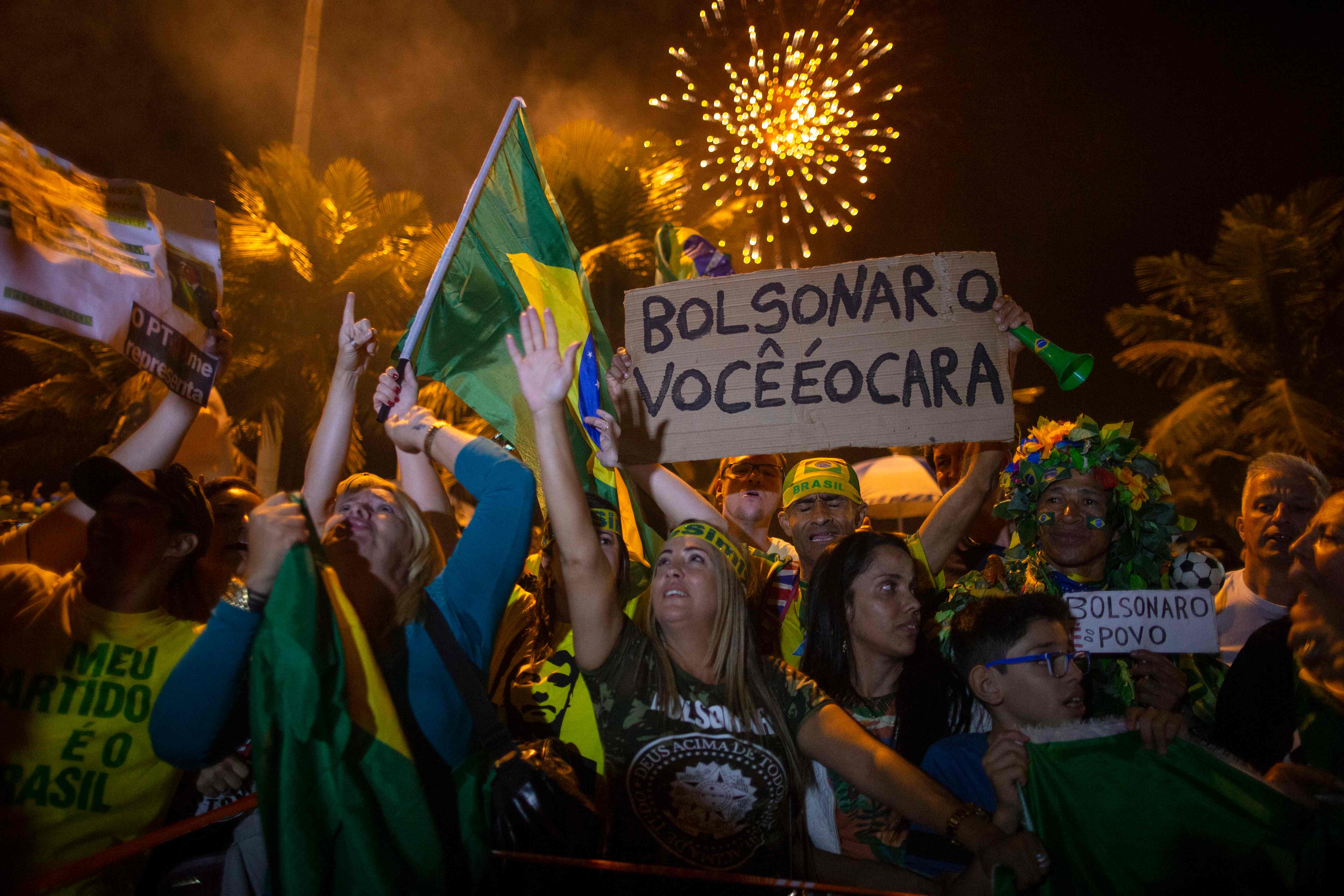 TOPSHOT - Supporters of far-right presidential candidate Jair Bolsonaro, celebrate in front of his house in Rio de Janeiro, Brazil, after he won Brazil's presidential election, on October 28, 2018. - Far-right former army captain Jair Bolsonaro was elected president of Brazil on Sunday, beating leftist opponent Fernando Haddad in a runoff election after a bitter and polarized campaign. Official results gave the controversial president-elect 55.18 percent of the vote with more than 99.7 percent of the ballots counted. (Photo by Mauro Pimentel / AFP)