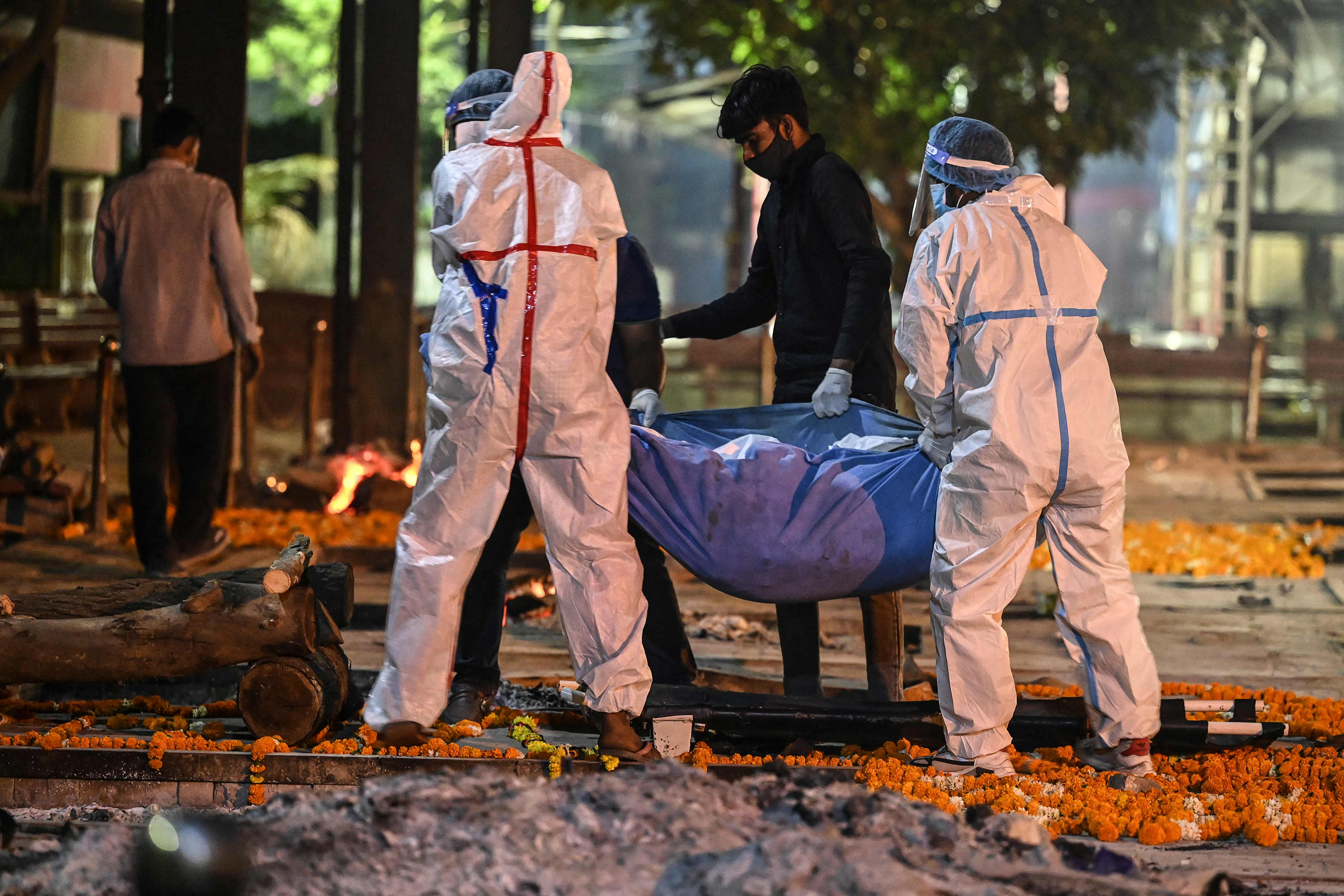Relatives and family members carry the dead body of a Covid-19 victim for a cremation at Nigambodh Ghat Crematorium, on the banks of the Yamuna river in New Delhi in the early hour of April 22, 2021. (Photo by SAJJAD HUSSAIN / AFP)