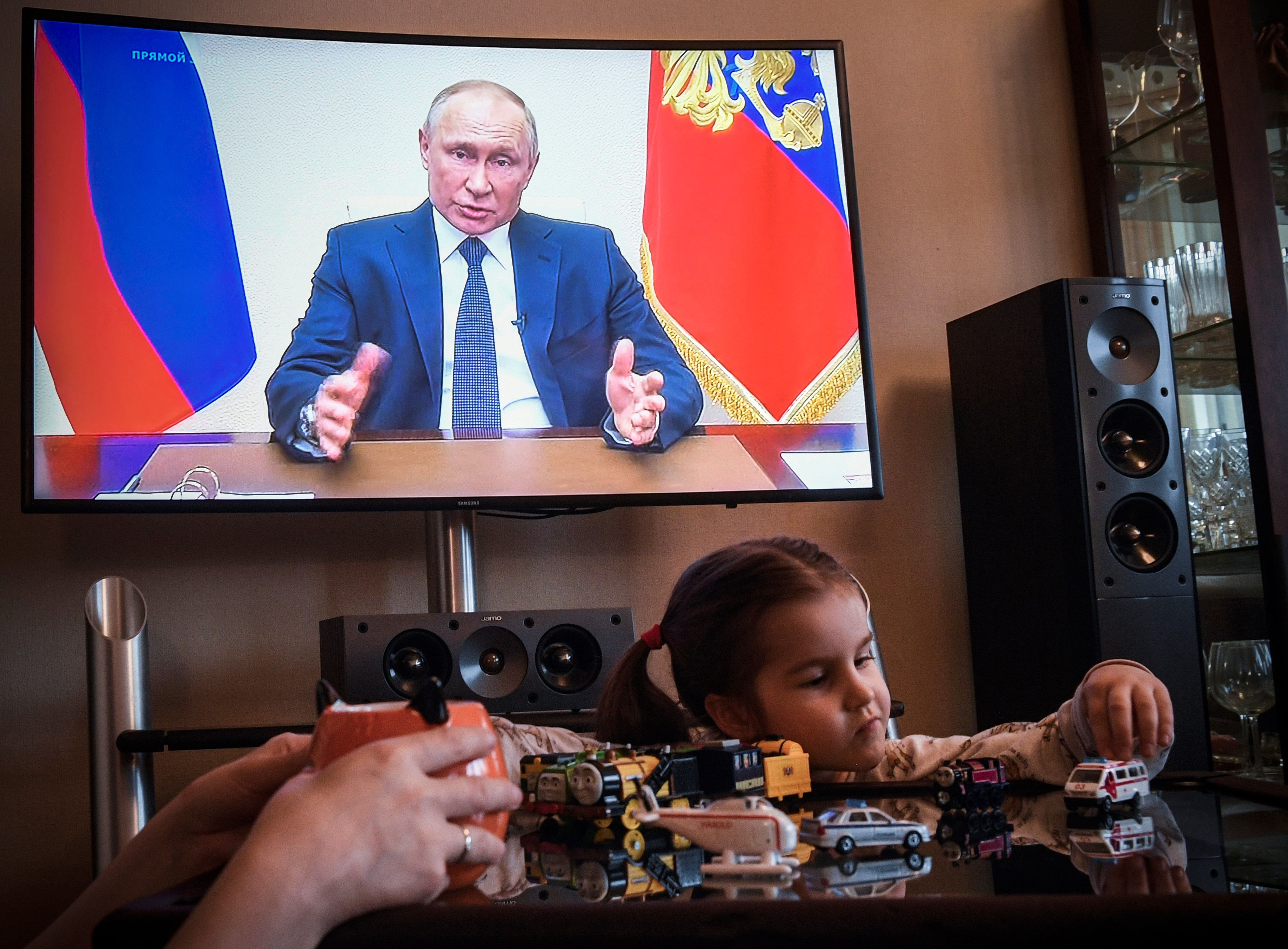 A woman watches a live broadcast of Russian President Vladimir Putin's address to the nation over the coronavirus outbreak, in her appartment in Moscow on April 2, 2020. - President Vladimir Putin on April 2, 2020 aid Russians will continue not going to work while receiving pay until the end of the month to contain the spread of the Covid-19 pandemic caused by the novel coronavirus. (Photo by Alexander NEMENOV / AFP)