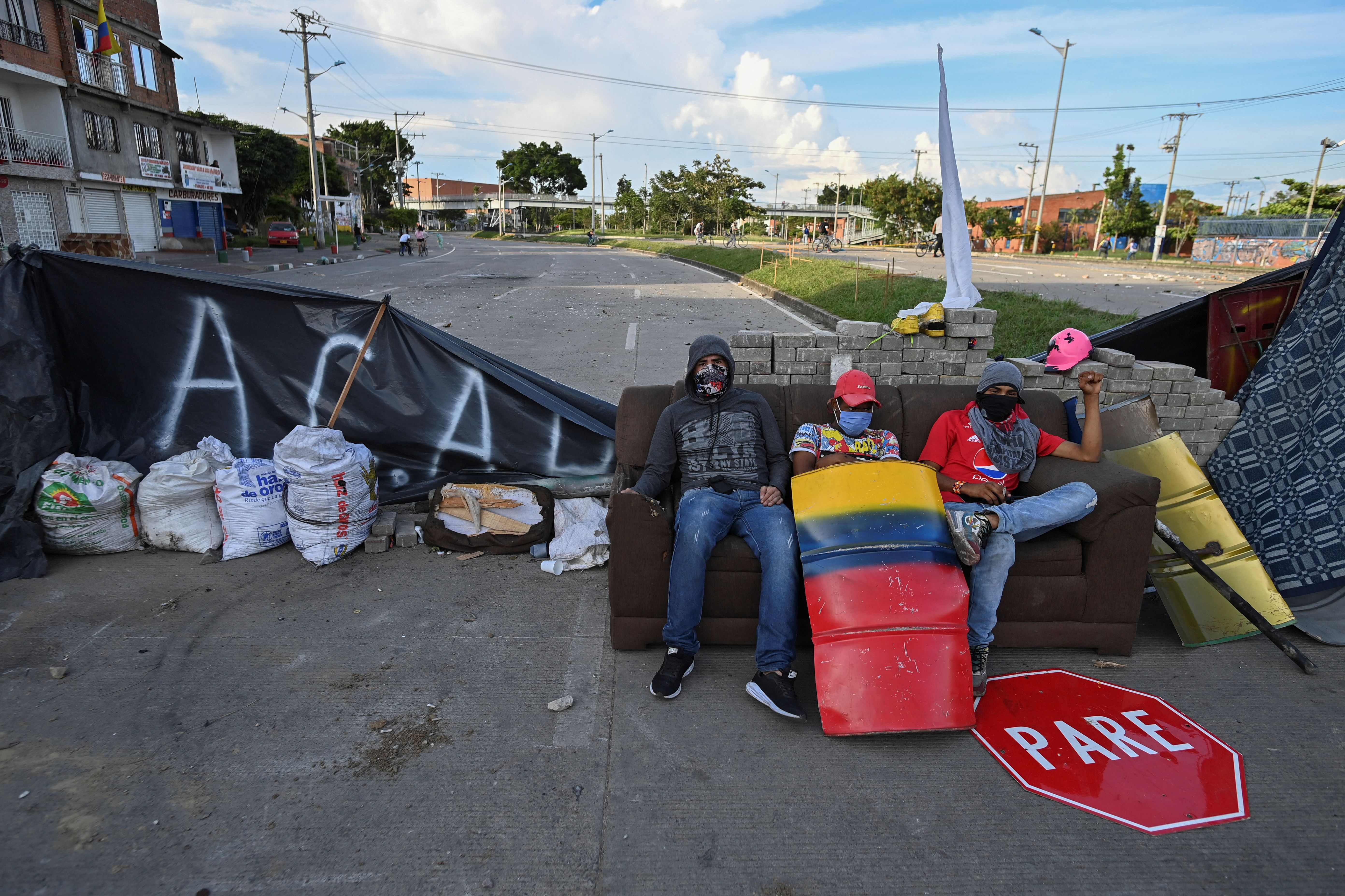 TOPSHOT - Demonstrators sit in a couch place at a barricade blocking a street during a protest against the government of Colombian President Ivan Duque in Cali, Colombia on June 2, 2021. - Night falls and the barricades of Cali, the focus of popular anger against the government in Colombia, exude fear. The shots "are fired in the early hours of the morning", say the demonstrators, who are keeping their eyes open. (Photo by Luis ROBAYO / AFP)