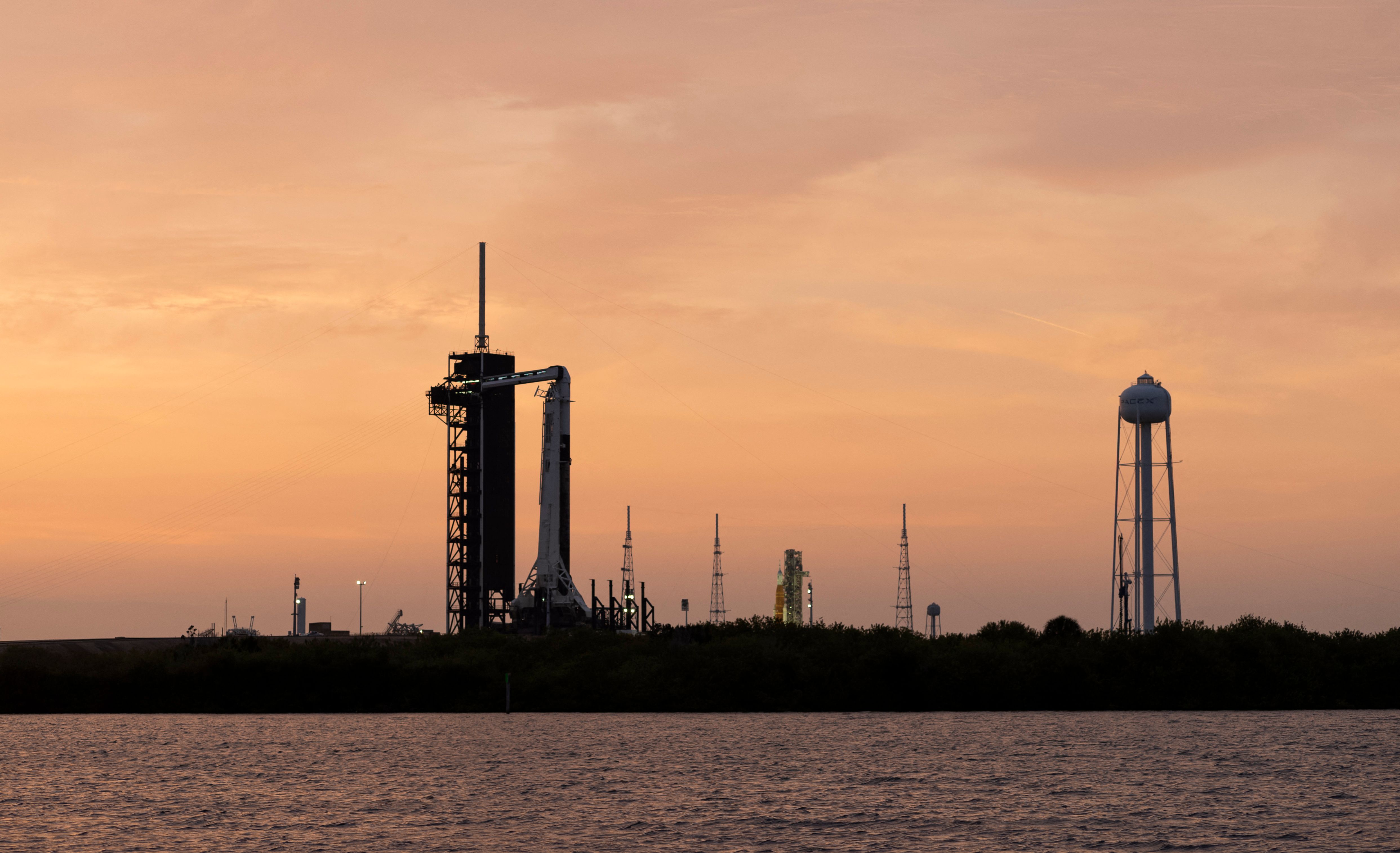 This handout image courtesy of NASA shows NASA�s Space Launch System (SLS) rocket with the Orion spacecraft aboard atop a mobile launcher at Launch Complex 39B as the Artemis I launch team prepares for the next attempt of the wet dress rehearsal test, right, as a SpaceX Falcon 9 rocket with the company's Crew Dragon spacecraft aboard is seen on the launch pad at Launch Complex 39A as preparations continue for Axiom Mission 1 (Ax-1), April 7, 2022, at NASA�s Kennedy Space Center in Florida. - The Ax-1 mission is the first private astronaut mission to the International Space Station. Ax-1 crew members Commander Michael L�pez-Alegr�a of Spain and the United States, Pilot Larry Connor of the United States, and Mission Specialists Eytan Stibbe of Israel, and Mark Pathy of Canada are scheduled to launch on April 8 from Launch Complex 39A at the Kennedy Space Center. (Photo by Joel KOWSKY / NASA / AFP) / RESTRICTED TO EDITORIAL USE - MANDATORY CREDIT "AFP PHOTO / Joel Kowsky / NASA " - NO MARKETING - NO ADVERTISING CAMPAIGNS - DISTRIBUTED AS A SERVICE TO CLIENTS