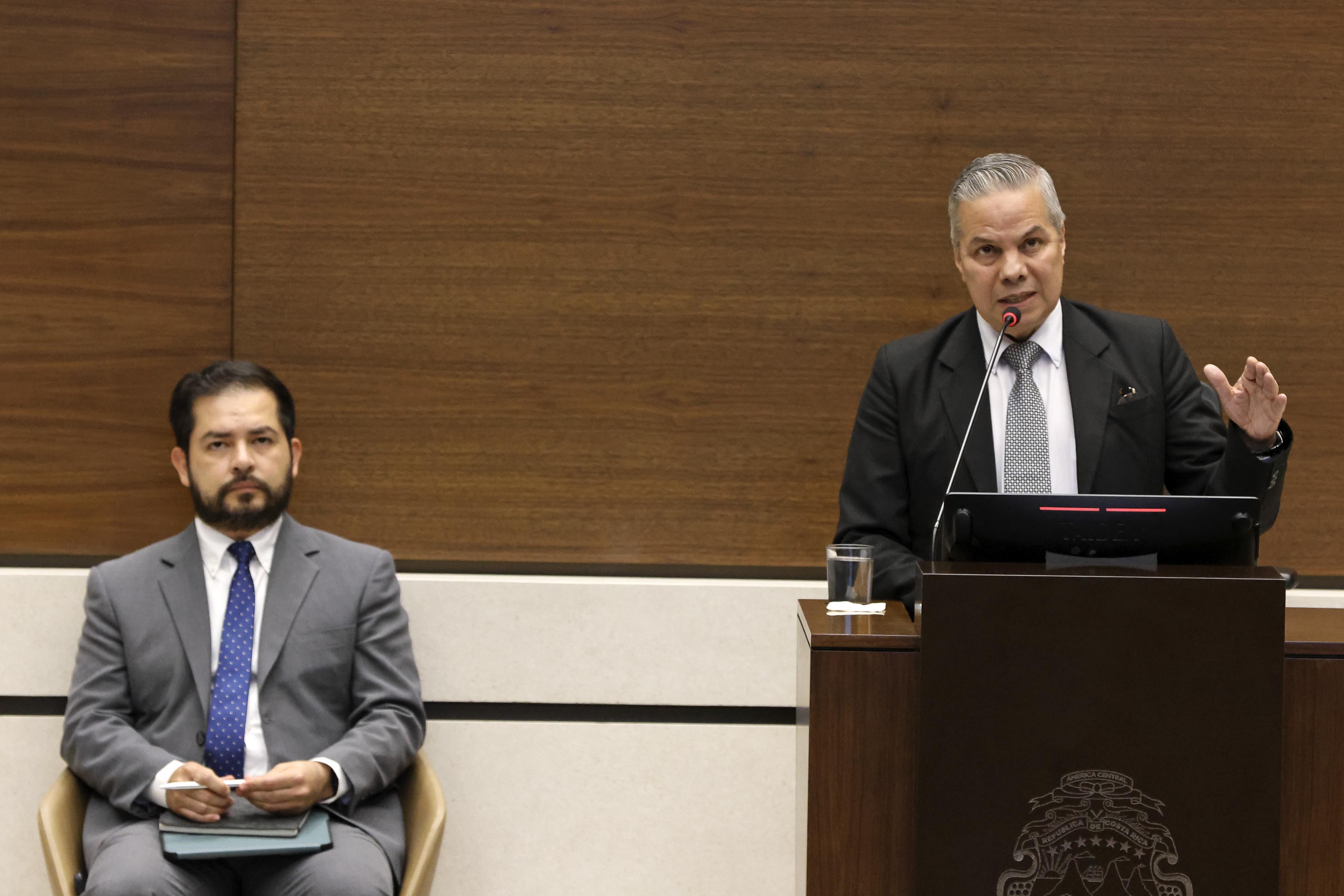 Roger Madrigal, presidente del Banco Central, habla en la Asamblea Legislativa. Alonso Alfaro, economista jefe de la entidad, lo escucha sentado detrás.