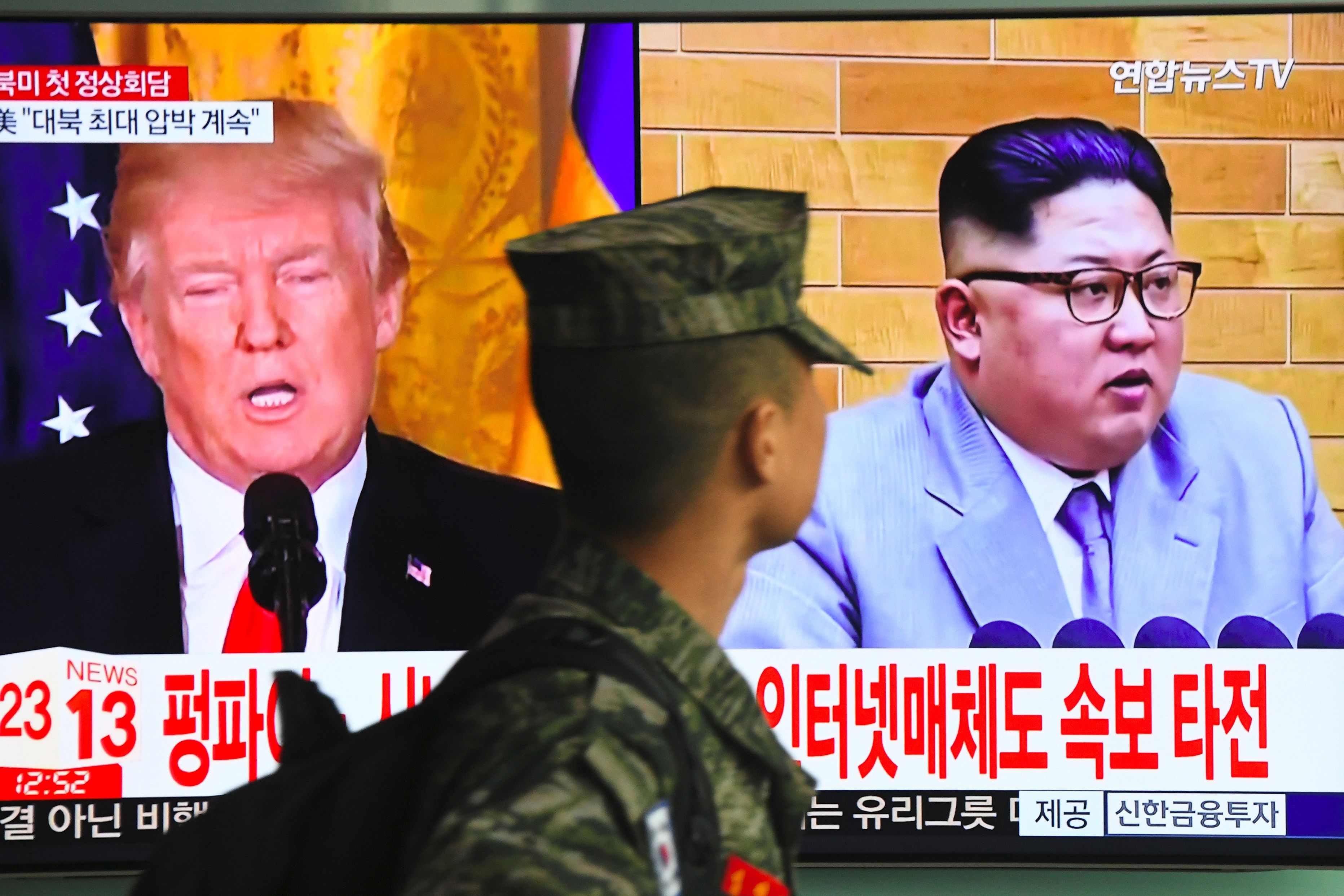 Un soldado surcoreano observa imágenes del presidente estadounidense, Donald Trump, y el líder norcoreano, Kim Jong-un, en una estación de tren en Seúl, el 9 de marzo del 2018.