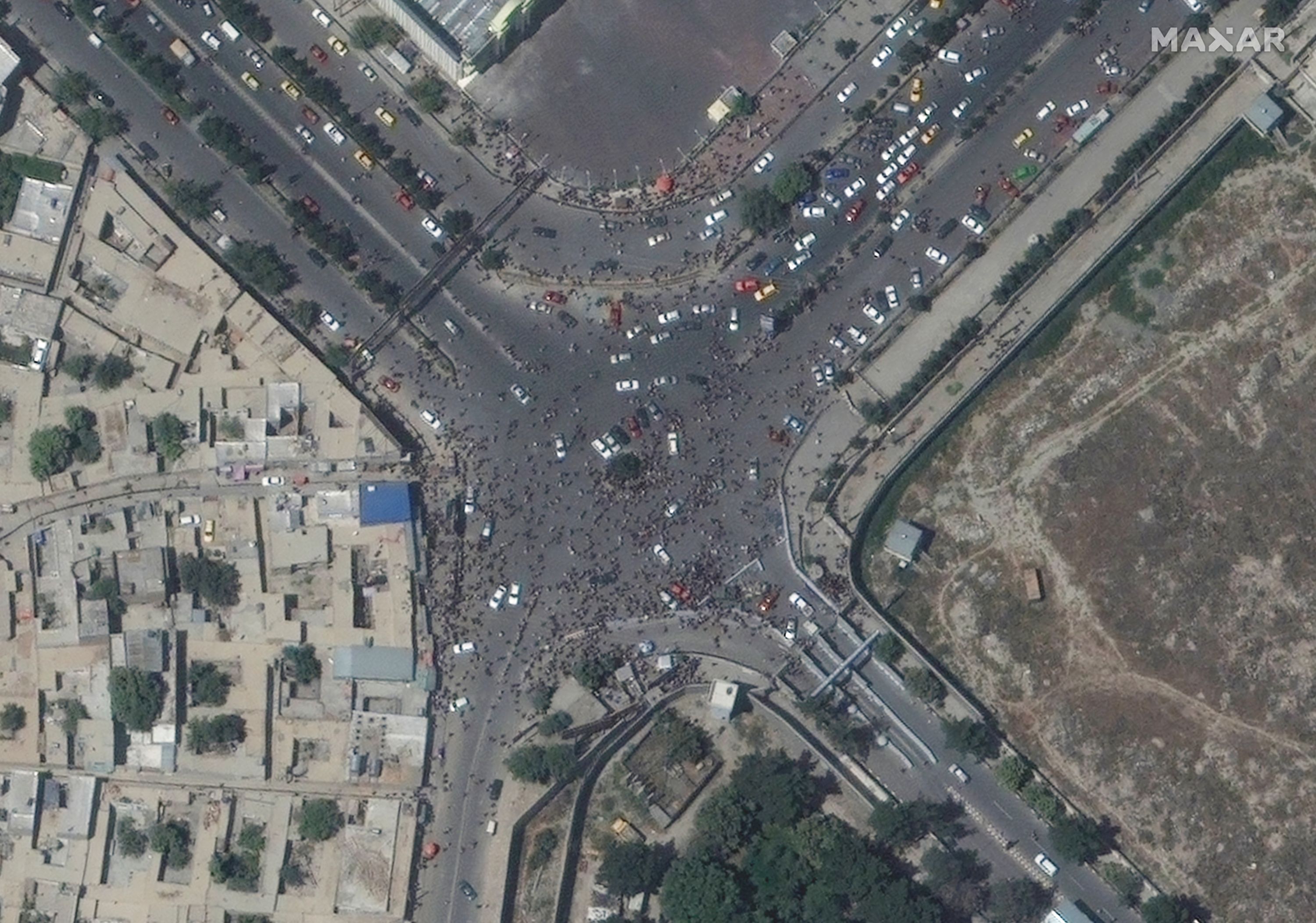 This handout satellite image released by Maxar Technologies shows crowds near the entrance, during the chaotic scene underway at Kabul�s Hamid Karzai International Airport in Afghanistan as thousands of people converged on the tarmac and airport runways as countries attempt to evacuate personnel from the city on August 16, 2021 - US soldiers killed two armed men at Kabul's airport on August 16, 2021 as thousands of people flocked to the terminal seeking to flee Afghanistan, a Pentagon official said. (Photo by - / Satellite image �2021 Maxar Technologies / AFP) / RESTRICTED TO EDITORIAL USE - MANDATORY CREDIT "AFP PHOTO / Satellite image �2021 Maxar Technologies " - NO MARKETING - NO ADVERTISING CAMPAIGNS - DISTRIBUTED AS A SERVICE TO CLIENTS - The watermark may not be removed/cropped / THE WATERMARK MAY NOT BE REMOVED/CROPPED
