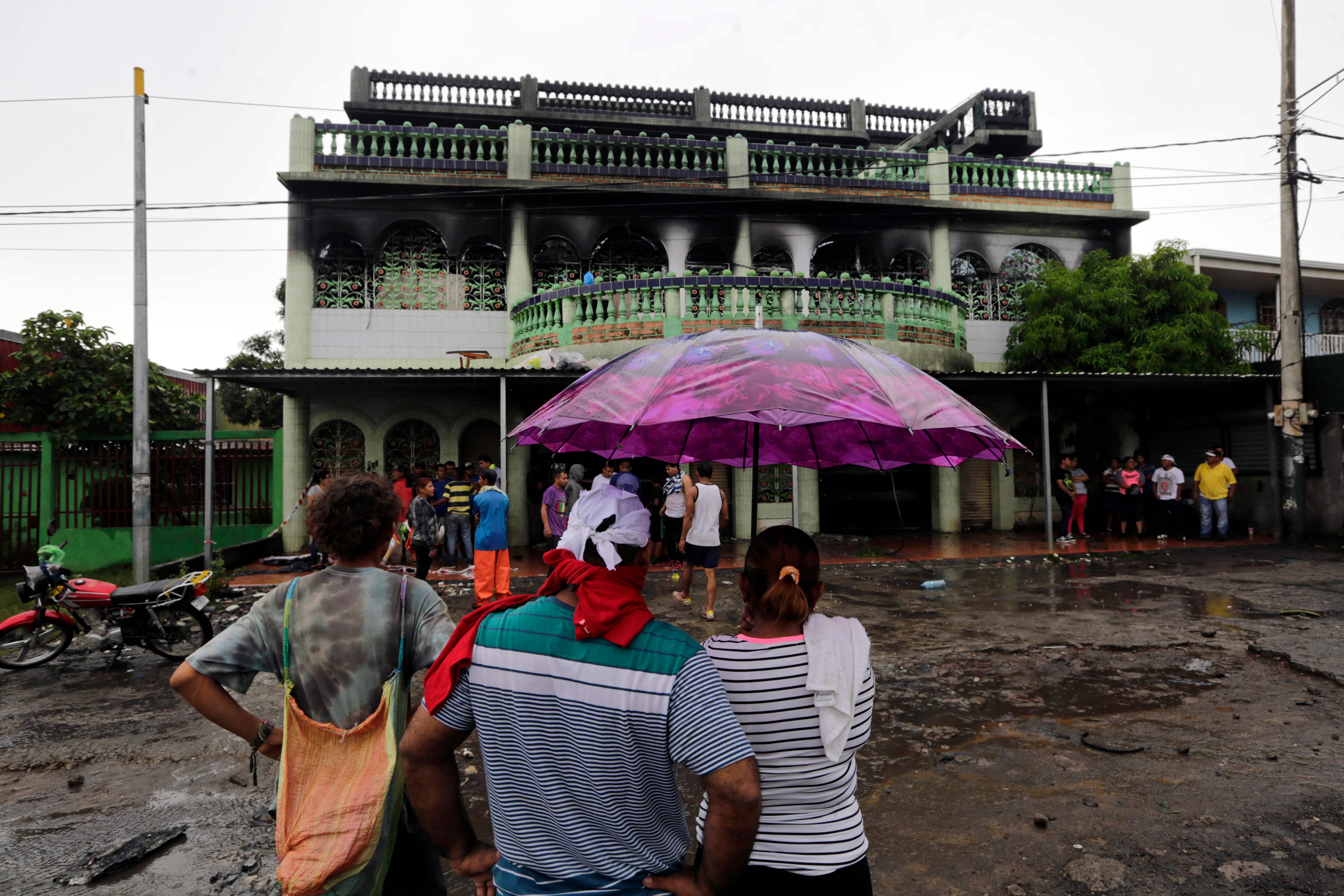 People look at a house burnt down under unclear circumstances and in which four adults and two children died, in the Carlos Marx neighborhood, in Managua on June 16, 2018. / AFP PHOTO / INTI OCON