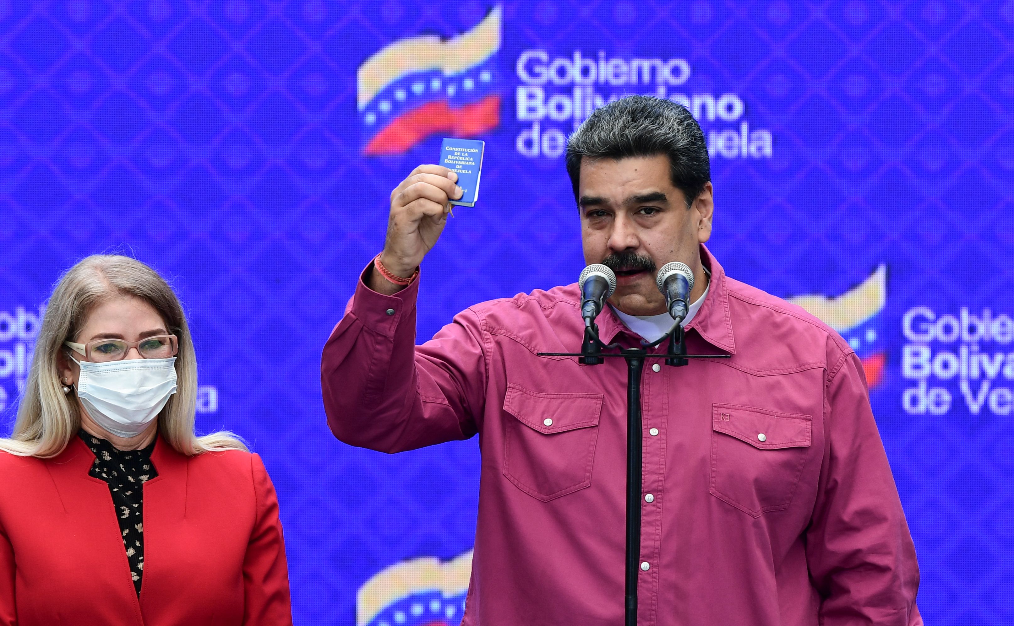 Venezuelan President Nicolas Maduro accompanied by his wife Cilia Flores (L) gestures while delivering a press conference at a polling station in the Simon Rodriguez school in Fuerte Tiuna, Caracas, on December 6, 2020 during Venezuela's legislative elections. - Polls opened early December 6 in legislative elections set to tighten Venezuelan President Nicolas Maduro's grip on power and weaken his US-backed rival, who is leading a boycott of the polls he calls a fraud. Maduro and his allies are set to dominate the legislative elections, which victory will give them control of the National Assembly, the only institution not yet in its hands. (Photo by Yuri CORTEZ / AFP)