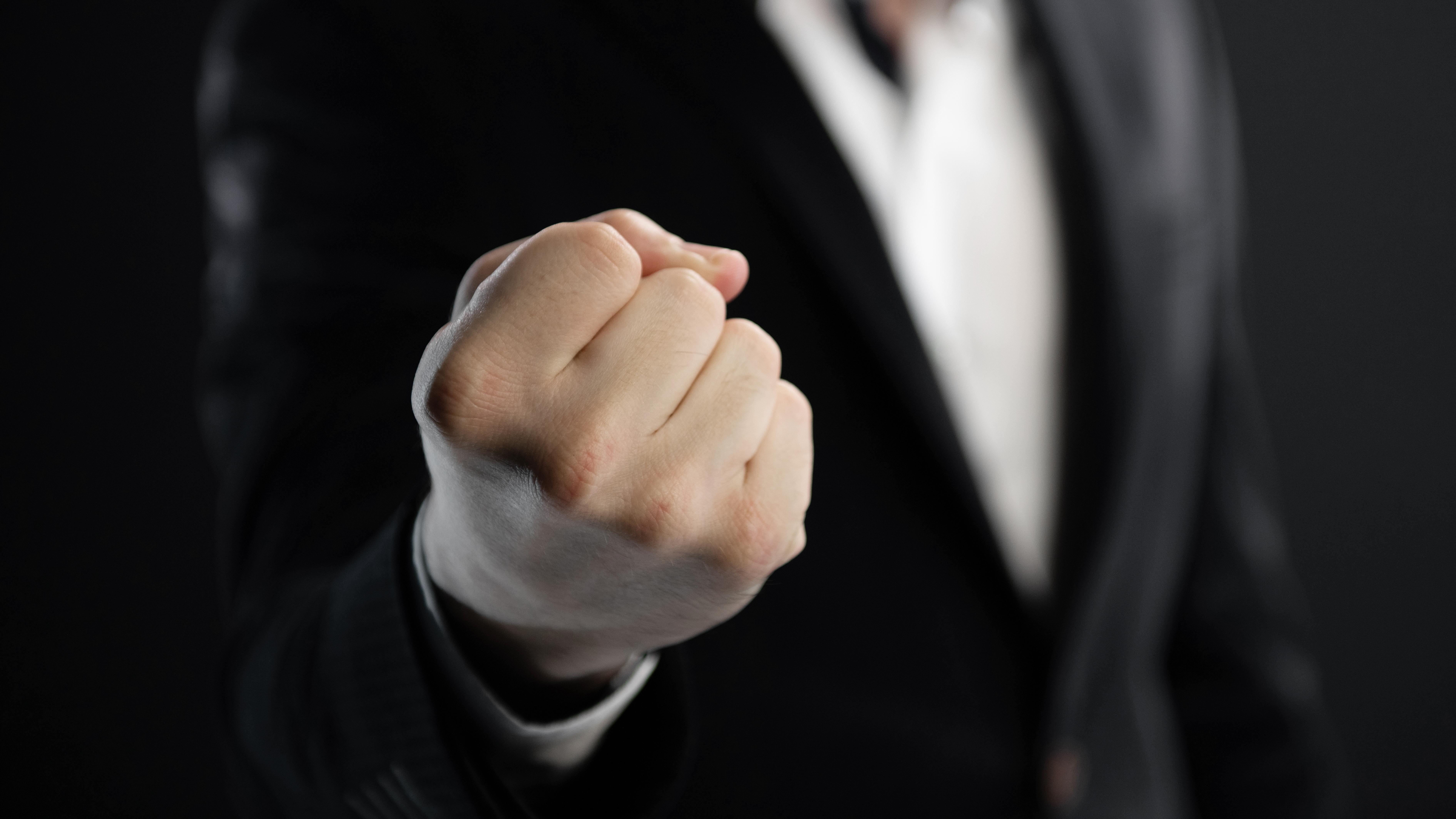 Puño apretado en primer plano, hombre con traje