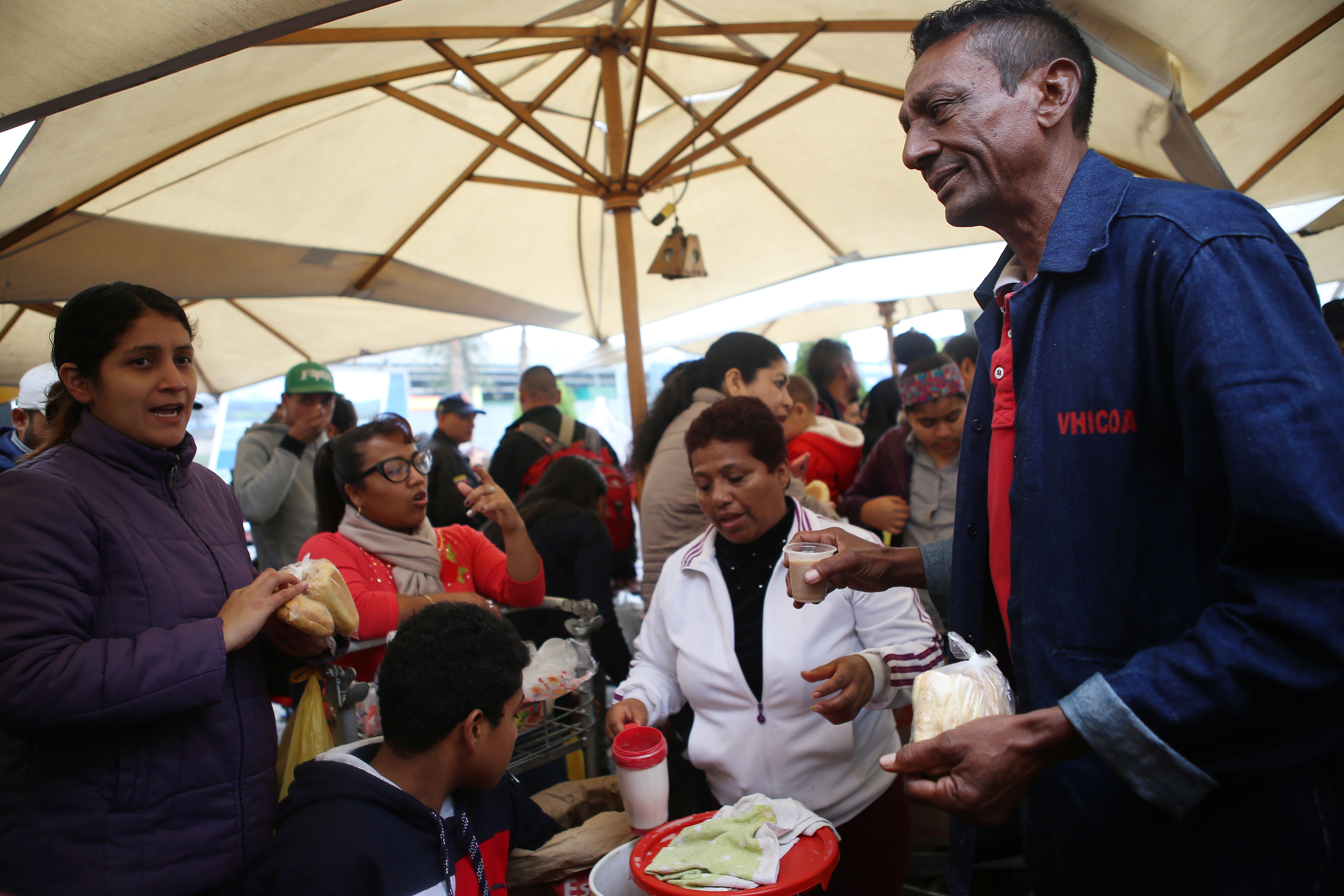 Venezuelan migrants get food from volunteers upon their arrival at the bus terminal in the north of Lima, after traveling for 20 hour from Tumbes, northwestern Peru, on August 26, 2018. - Venezuelan migrants denounced on Saturday that Ecuador "cheated" on them and delayed their transfer by road to Peru, which prevented them from crossing to that country before the passport requirement began to apply. (Photo by Teo BIZCA / AFP)