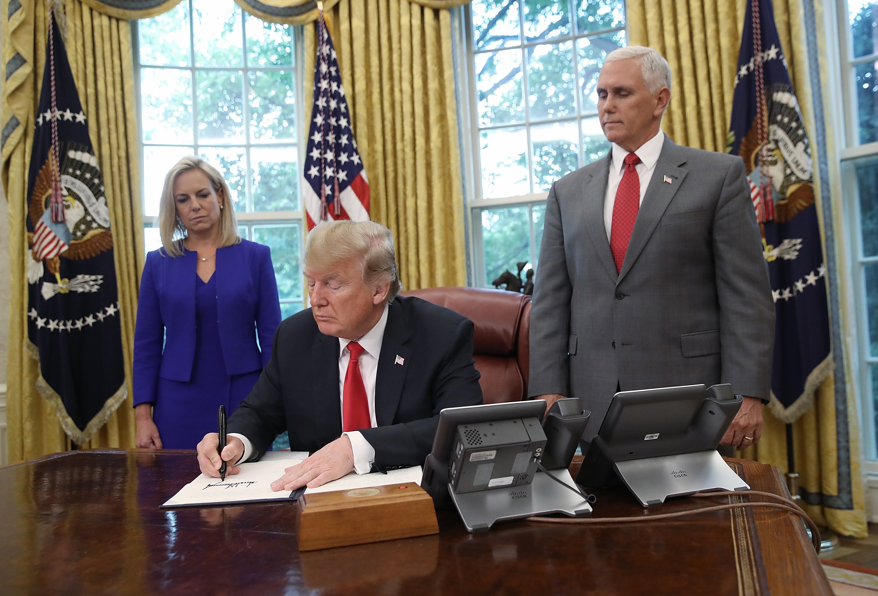 WASHINGTON, DC - JUNE 20: U.S. President Donald Trump, accompanied by Department of Homeland Security Secretary Kirstjen Nielsen (L) and U.S. Vice President Mike Pence (R), signs an executive order that will end the practice of separating family members who are apprehended while illegally entering the United States on June 20, 2018 in Washington, DC. The order would detain parents and children together. Win McNamee/Getty Images/AFP
== FOR NEWSPAPERS, INTERNET, TELCOS & TELEVISION USE ONLY ==