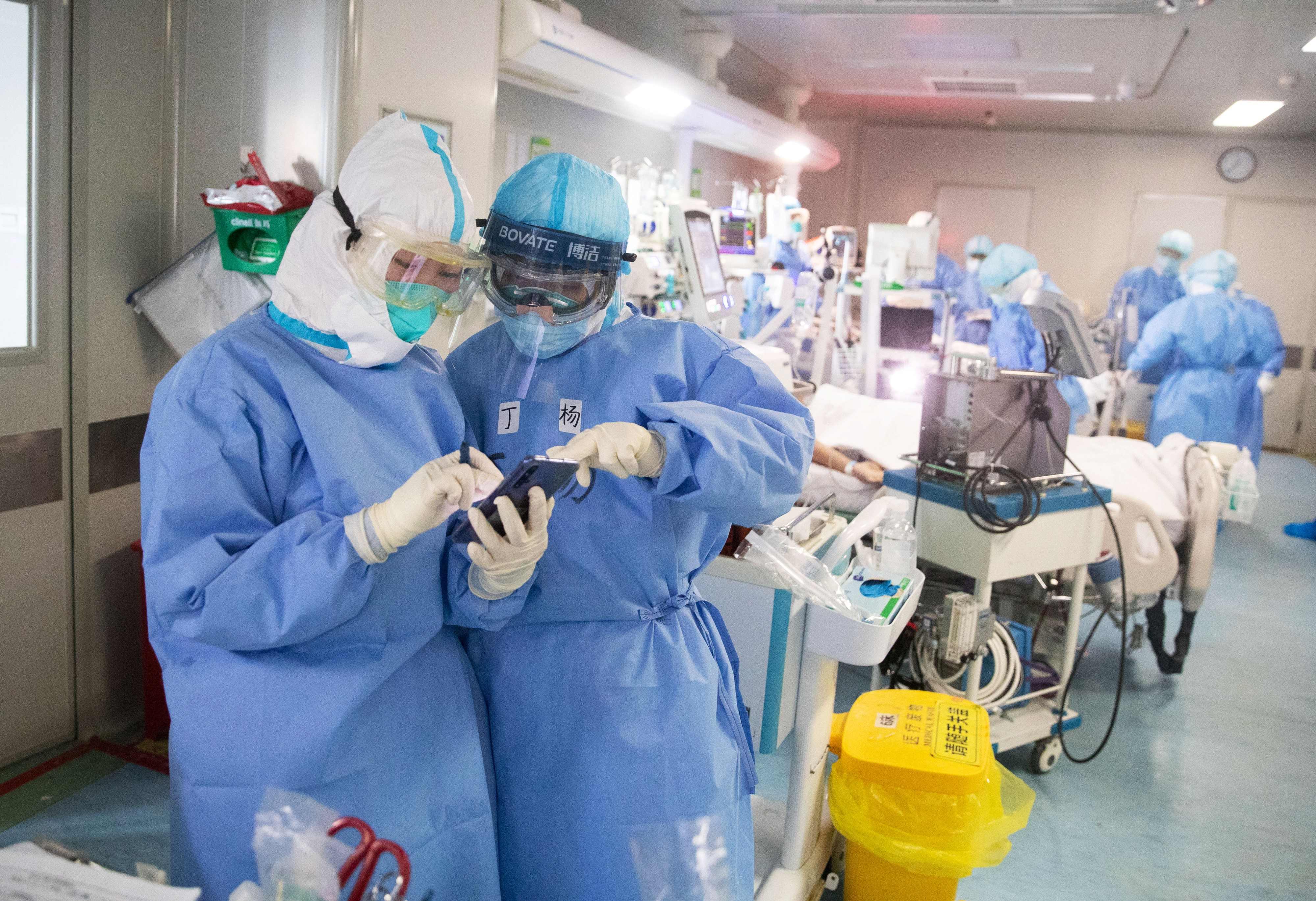 Medical staff treat check a mobile phone as they treat COVID-19 coronavirus patients at a hospital in Wuhan, in China's central Hubei province on March 19, 2020. - China on March 19 reported no new domestic cases of the coronavirus for the first time since it started recording them in January, but recorded a spike in infections from abroad. (Photo by STR / AFP) / China OUT