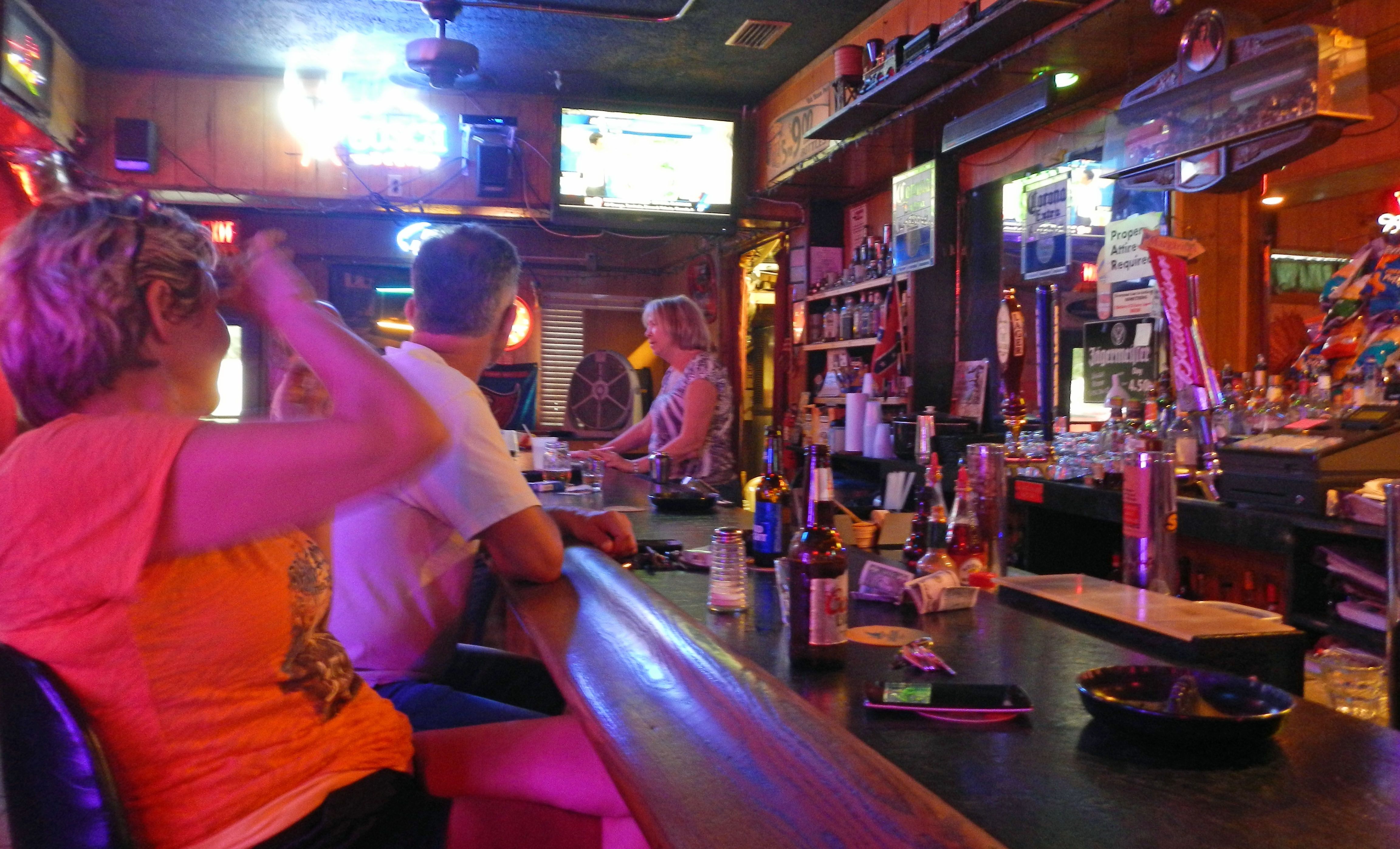 (FILES) In this file photo taken on October 6, 2016, people watch the news as they drink in a bar in Titusville, Florida, before the landfall of Hurricane Matthew. - Florida said Friday it is banning the consumption of alcohol in bars as coronavirus cases spike in the state. (Photo by BRUCE WEAVER / AFP)