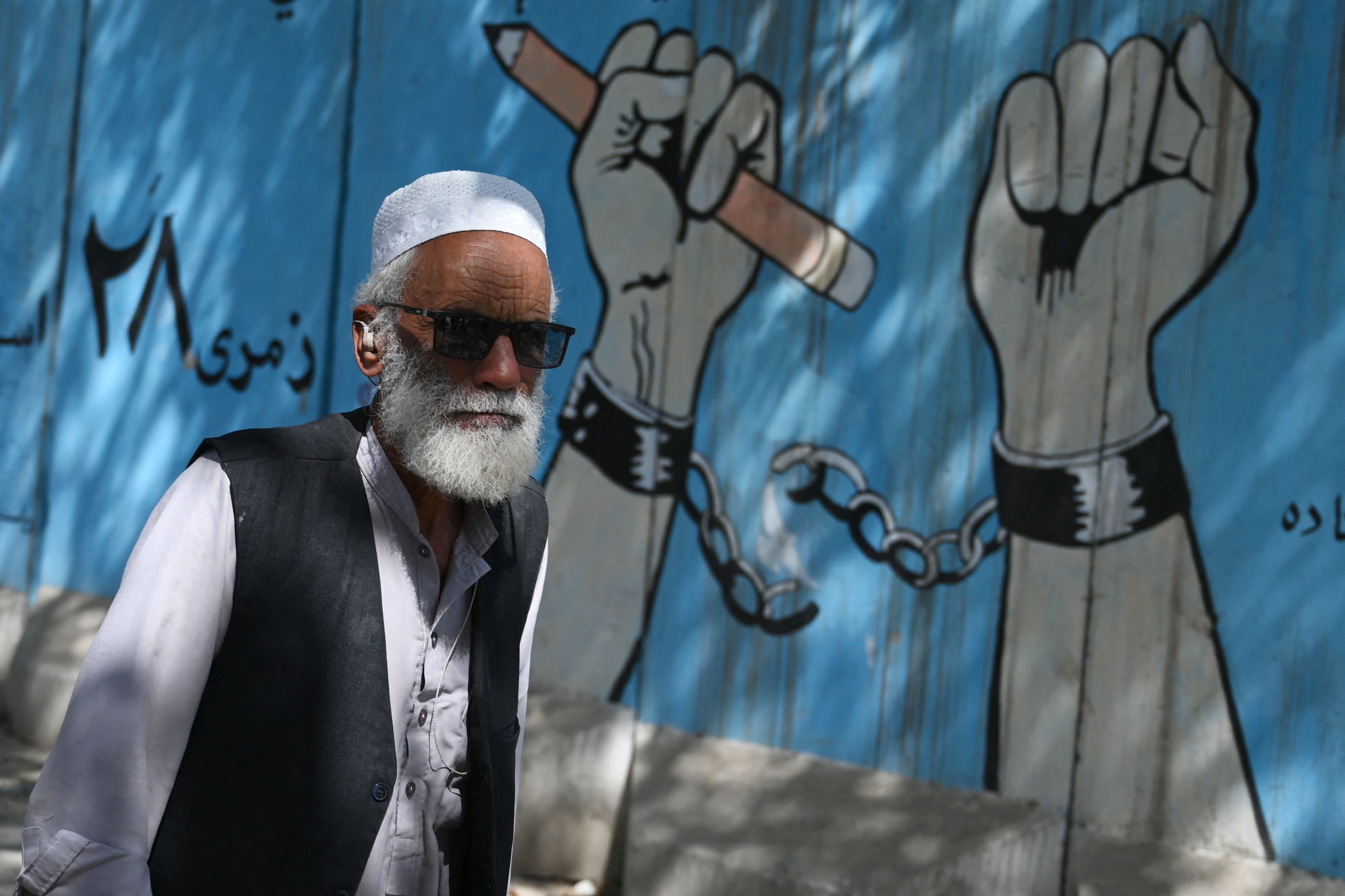 A walks past a mural outside Afghanistan's Ministry of Higher Education in Kabul on September 9, 2021. (Photo by WAKIL KOHSAR / AFP)