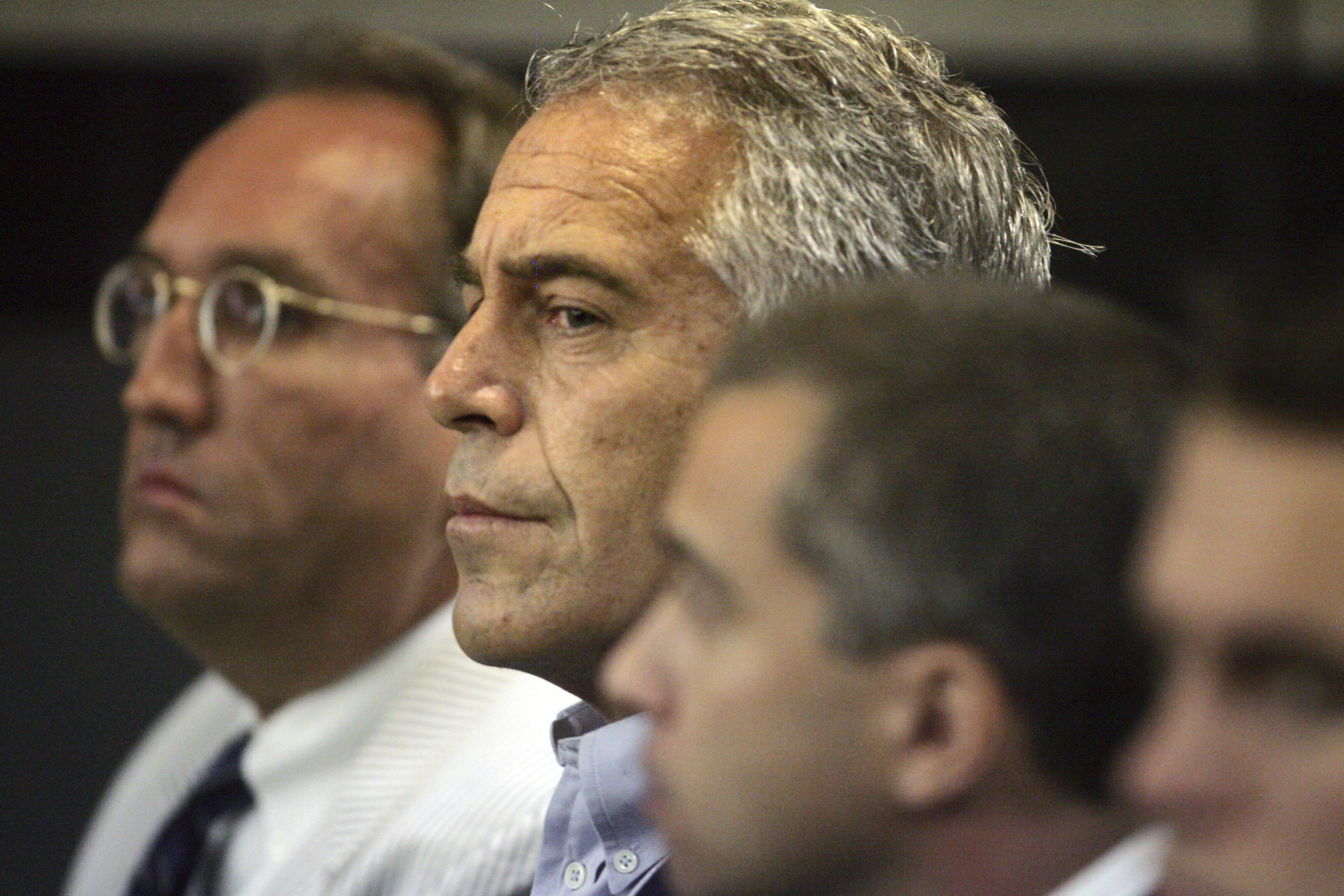 FILE - In this July 30, 2008 file photo, Jeffrey Epstein, center, is shown in custody in West Palm Beach, Fla. The wealthy financier and convicted sex offender has been arrested in New York on sex trafficking charges. Two law enforcement officials said Epstein was taken into federal custody Saturday, July 6, 2019, on charges involving sex-trafficking allegations that date to the 2000s. (Uma Sanghvi/Palm Beach Post via AP, File)