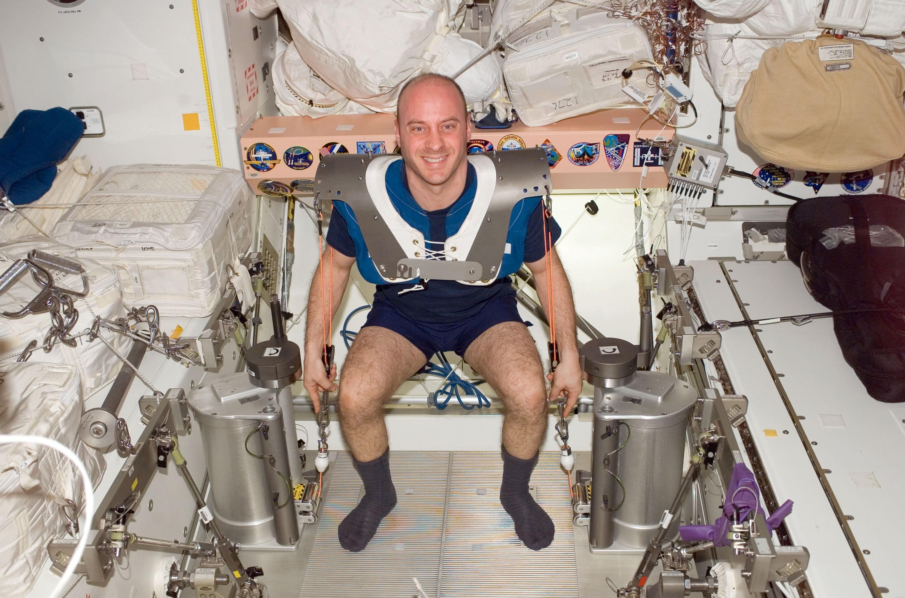 El astronauta de NASA Garrett Reisman, ingeniero de vuelo de la Expedición 17, usando almohadillas de arnés achaparradas, realiza flexiones de rodilla utilizando el equipo del Dispositivo de Ejercicio Resistivo Provisional (IRED) en el nodo Unity de la Estación Espacial Internacional.