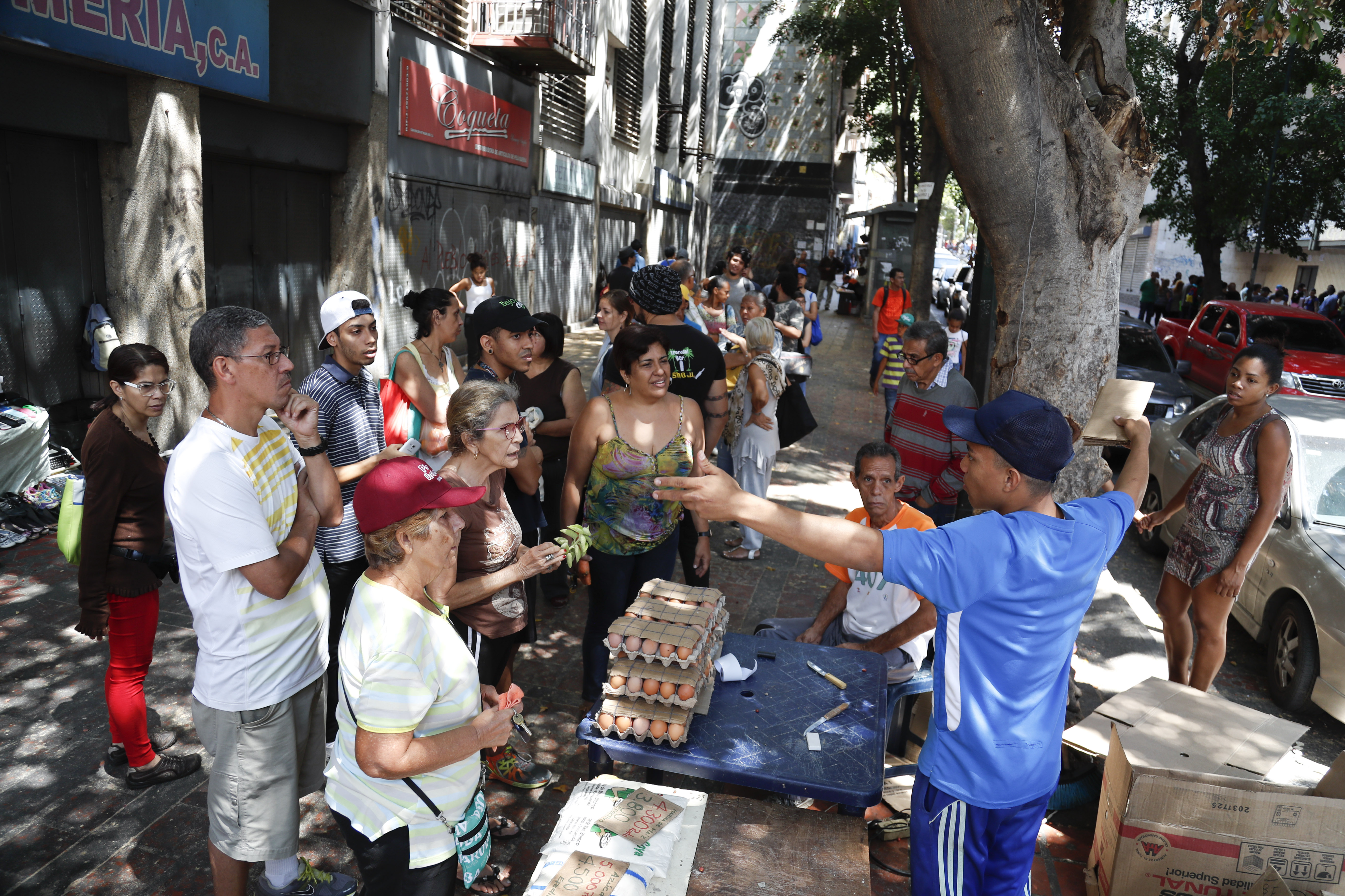 A food vendor tells shoppers he can't accept their debit cards, the most common form of payment due to inflation, during an electricity blackout in Caracas, Venezuela, Sunday, March 10, 2019. Power and communications outages continue to hit Venezuela, intensifying the hardship of a country paralyzed by economic and political crisis and heightening tension between the bitterly divided factions which accuse each other of being responsible for the collapse of the power grid. (AP Photo/Eduardo Verdugo)