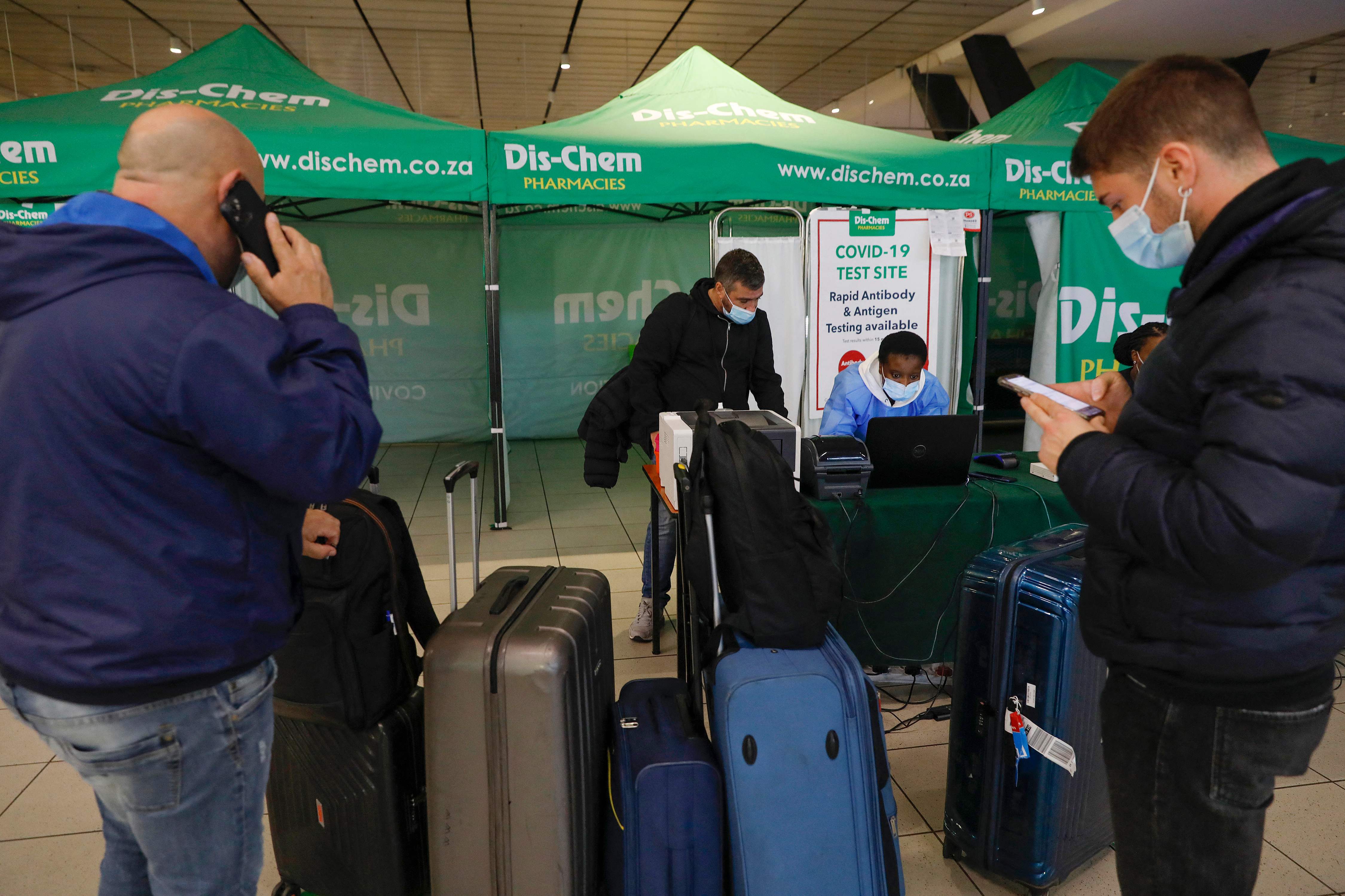 A healthcare worker assists a traveller to obtain his test results after conducting a polymerase chain reaction (PCR) Covid-19 test at OR Tambo International Airport in Johannesburg on November 27, 2021, after several countries banned flights from South Africa following the discovery of a new Covid-19 variant Omicron. - A flurry of countries around the world have banned ban flights from southern Africa following the discovery of the variant, including the United States, Canada, Australia,Thailand, Brazil and several European countries. The main countries targeted by the shutdown include South Africa, Botswana, eSwatini (Swaziland), Lesotho, Namibia, Zambia, Mozambique, Malawi and Zimbabwe. (Photo by Phill Magakoe / AFP)