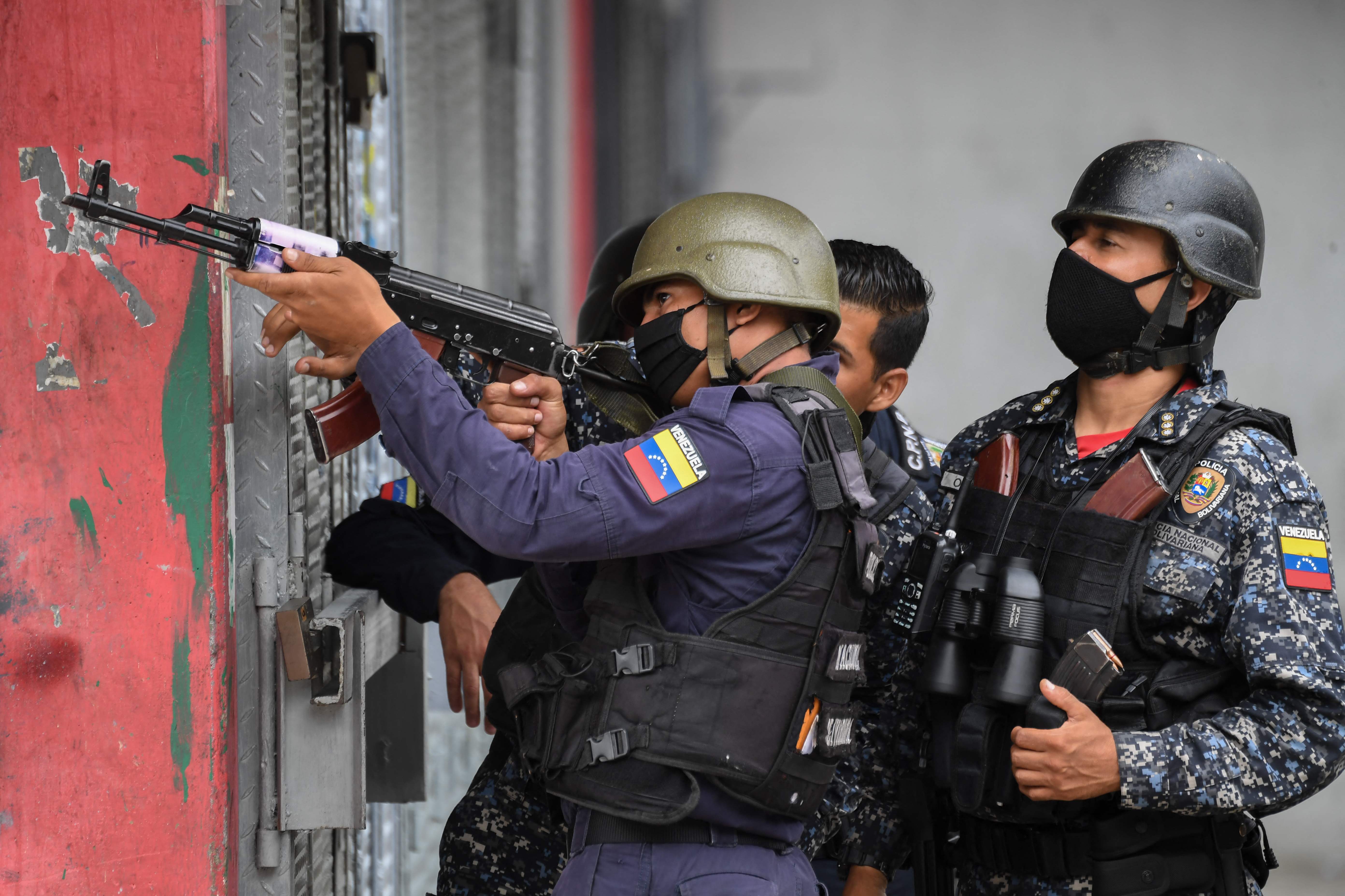 (FILES) In this file photo taken on July 09, 2021 Members of the Bolivarian National Police aim at possibe targets after clashes with alleged members of a criminal gang at the Cota 905 neighborhood in Caracas on July 9, 2021. - Confrontations between criminal gangs and authority forces have made poor neighborhoods in Venezuela become a hail of bullets. (Photo by Federico PARRA / AFP)